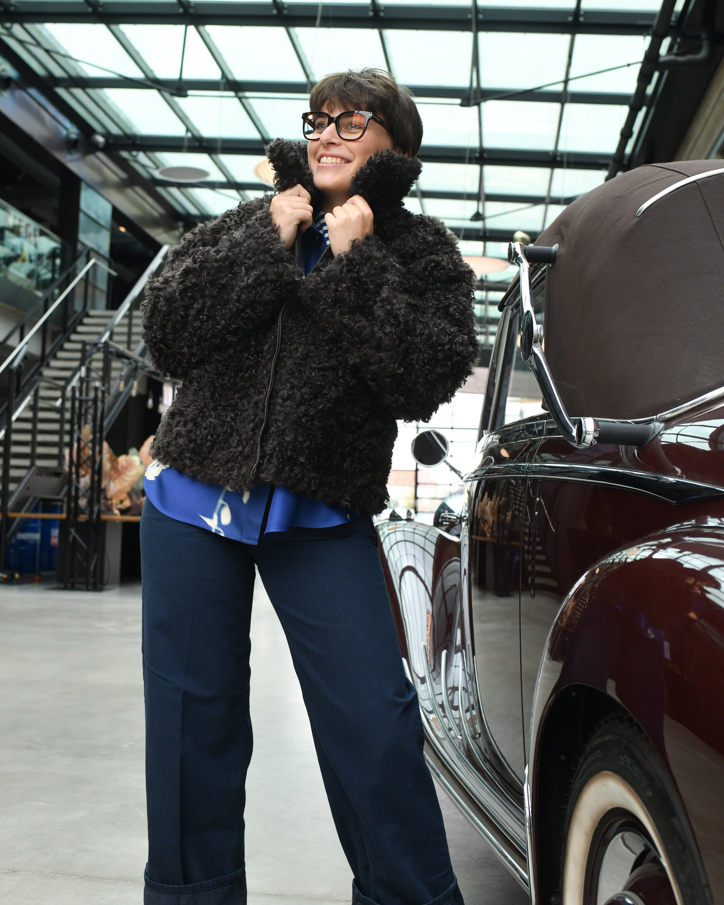 Frau mit dunkelblauer Jeans, blauer Seidenbluse und dunkelbrauner Ksucheljacke