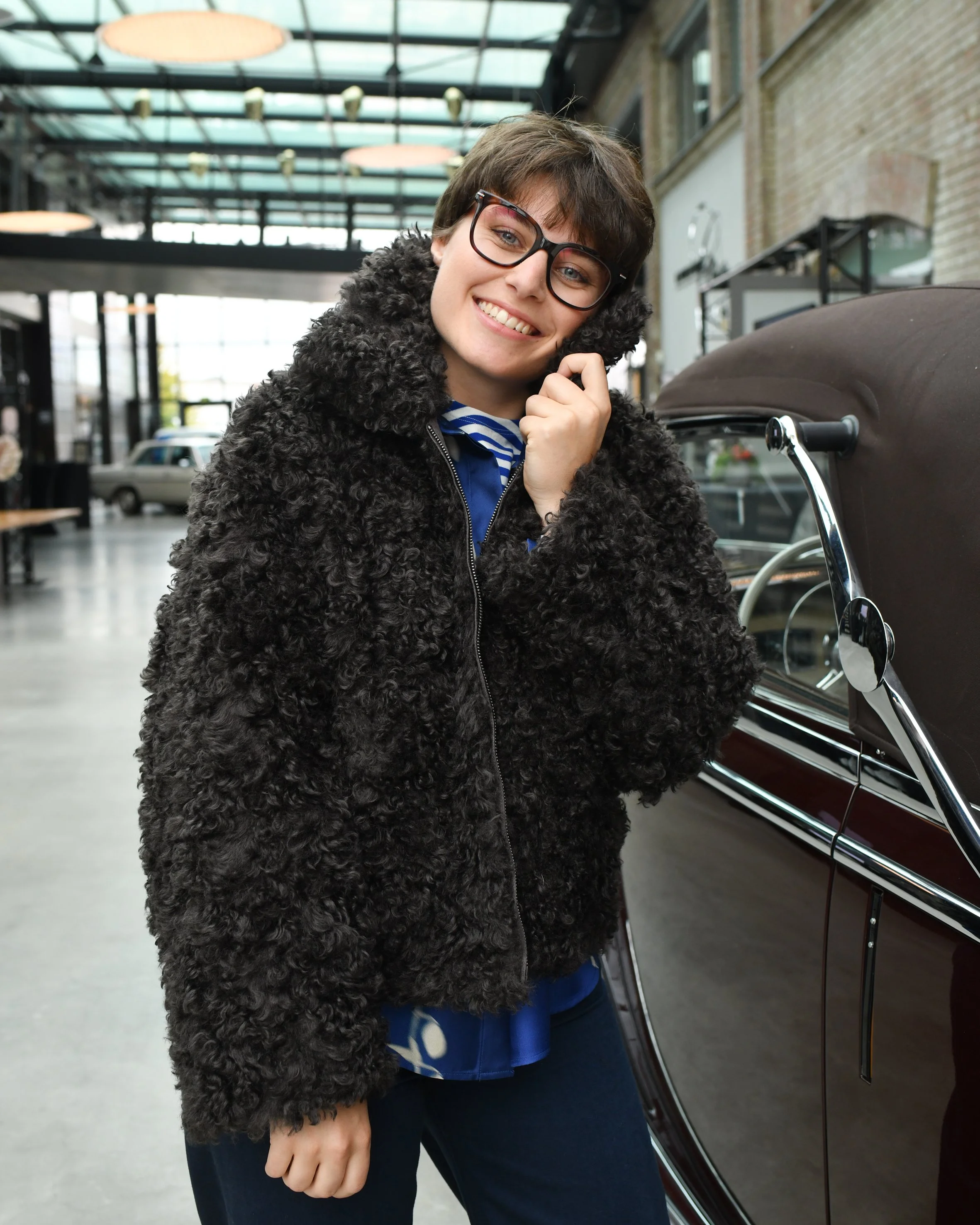 Frau mit dunkelblauer Jeans, blauer Seidenbluse und dunkelbrauner Ksucheljacke