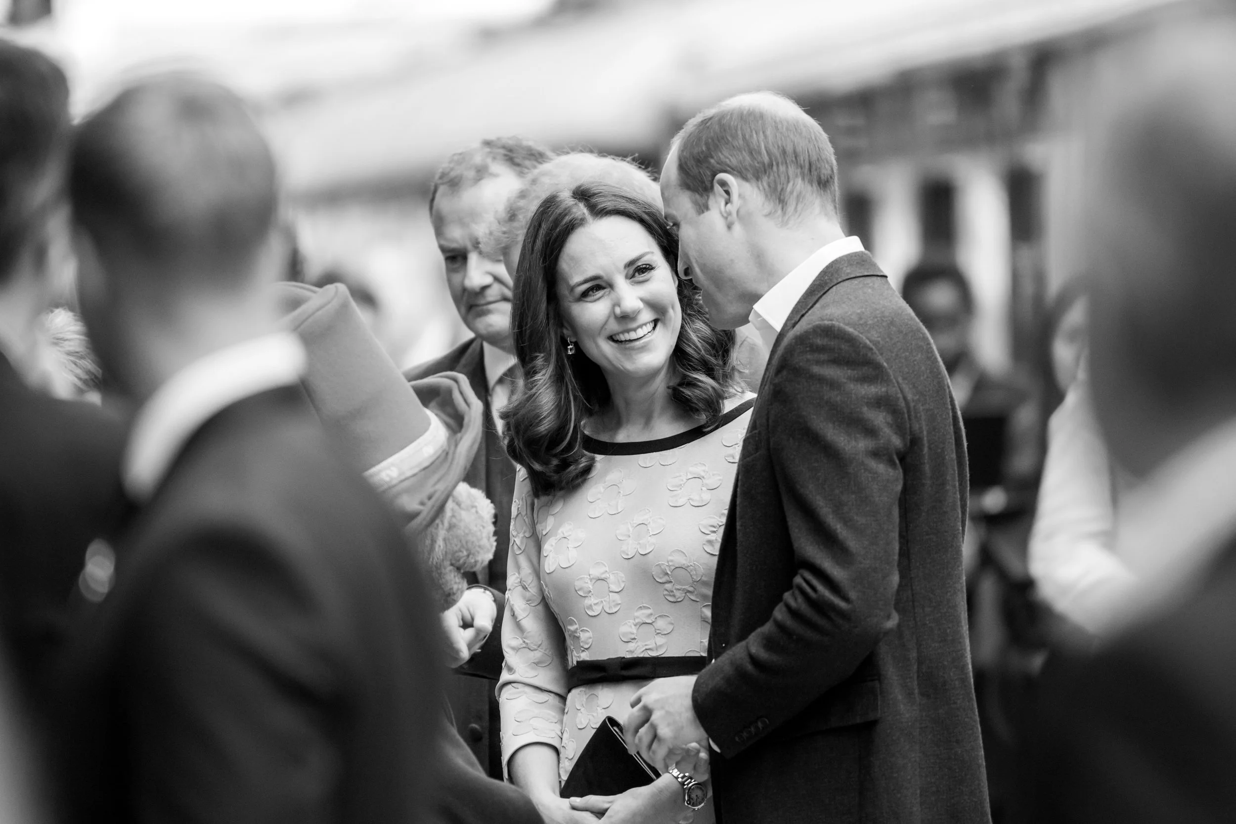 A man and woman are smiling and talking at a social gathering.