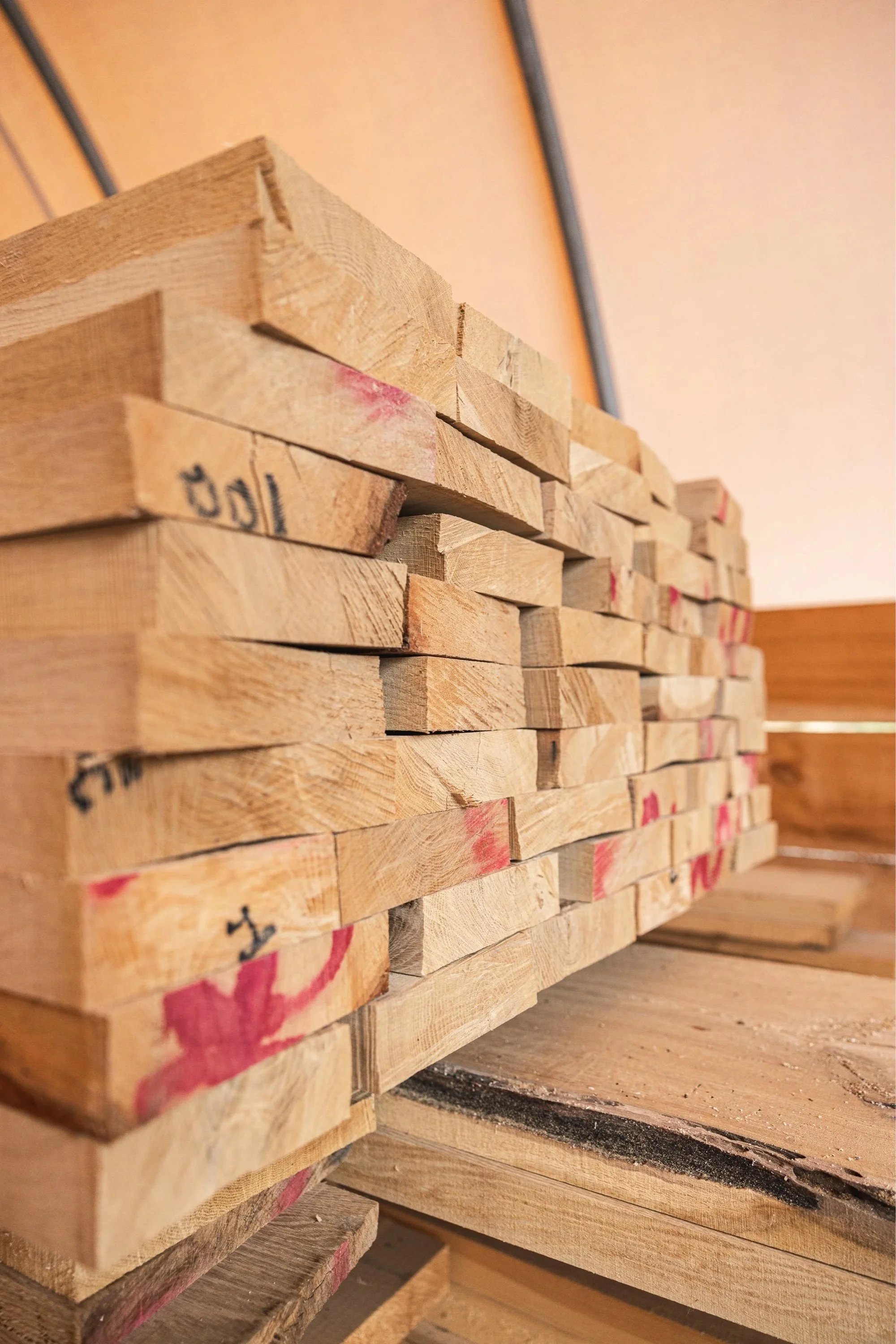 Stack of wooden planks on a workbench in a woodworking shop.