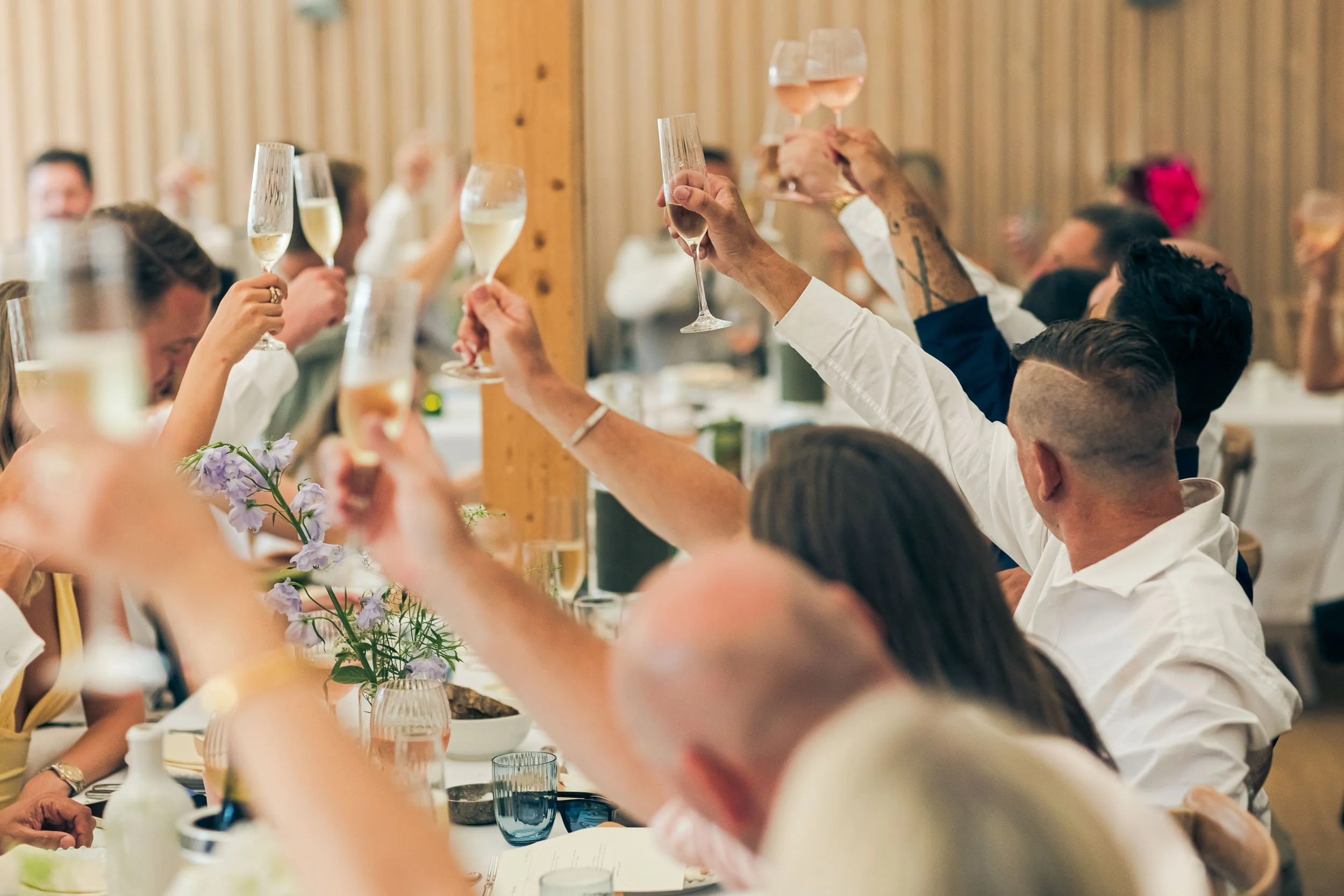People at a celebration raising champagne glasses in a toast at a decorated gathering table.