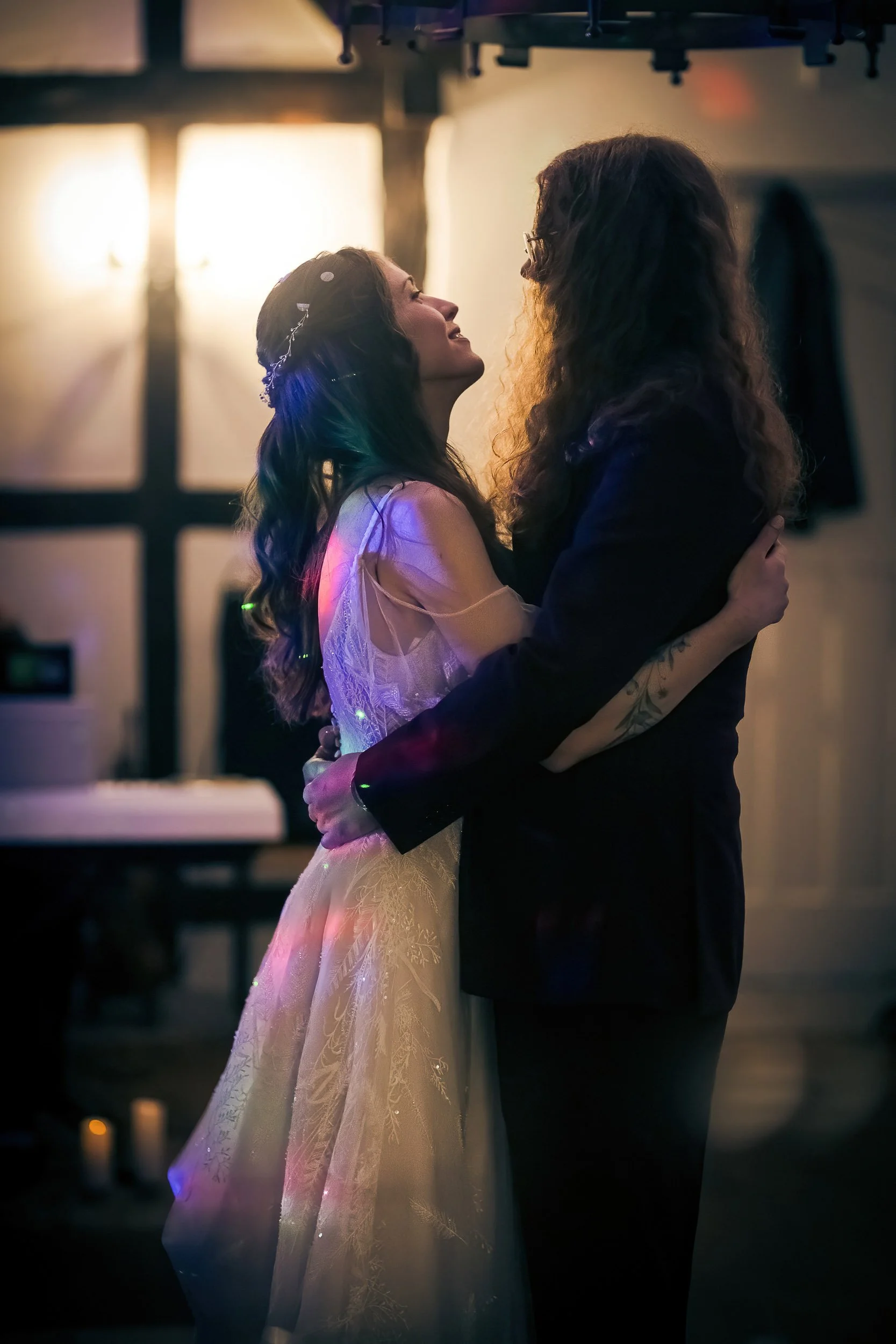 A couple dancing closely at a wedding reception, with warm lighting and a blurred background.