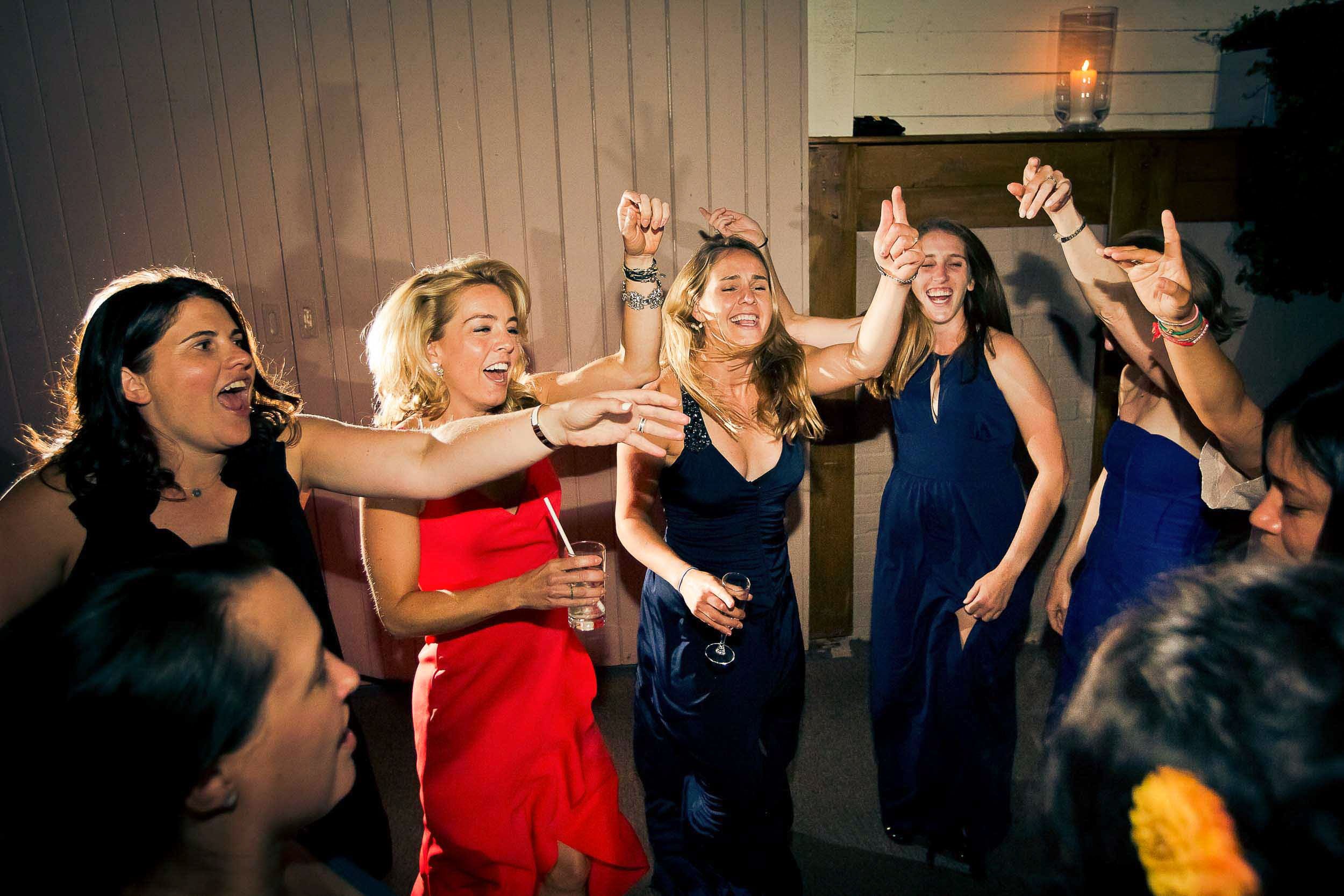 Group of women dancing and singing at a party, wearing elegant dresses