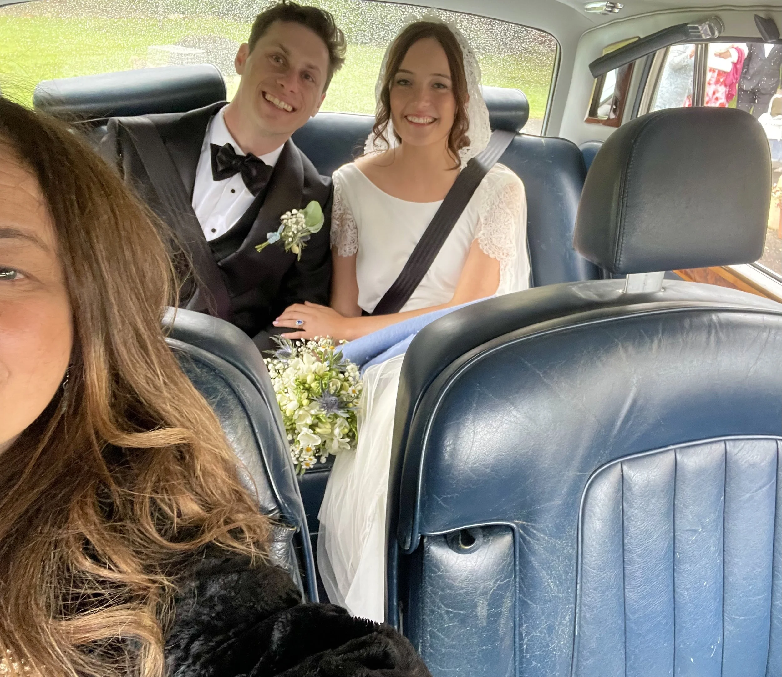 Chauffeuse -female chauffeur- driving bride and groom in vintage Rolls Royce with blue leather upholstery