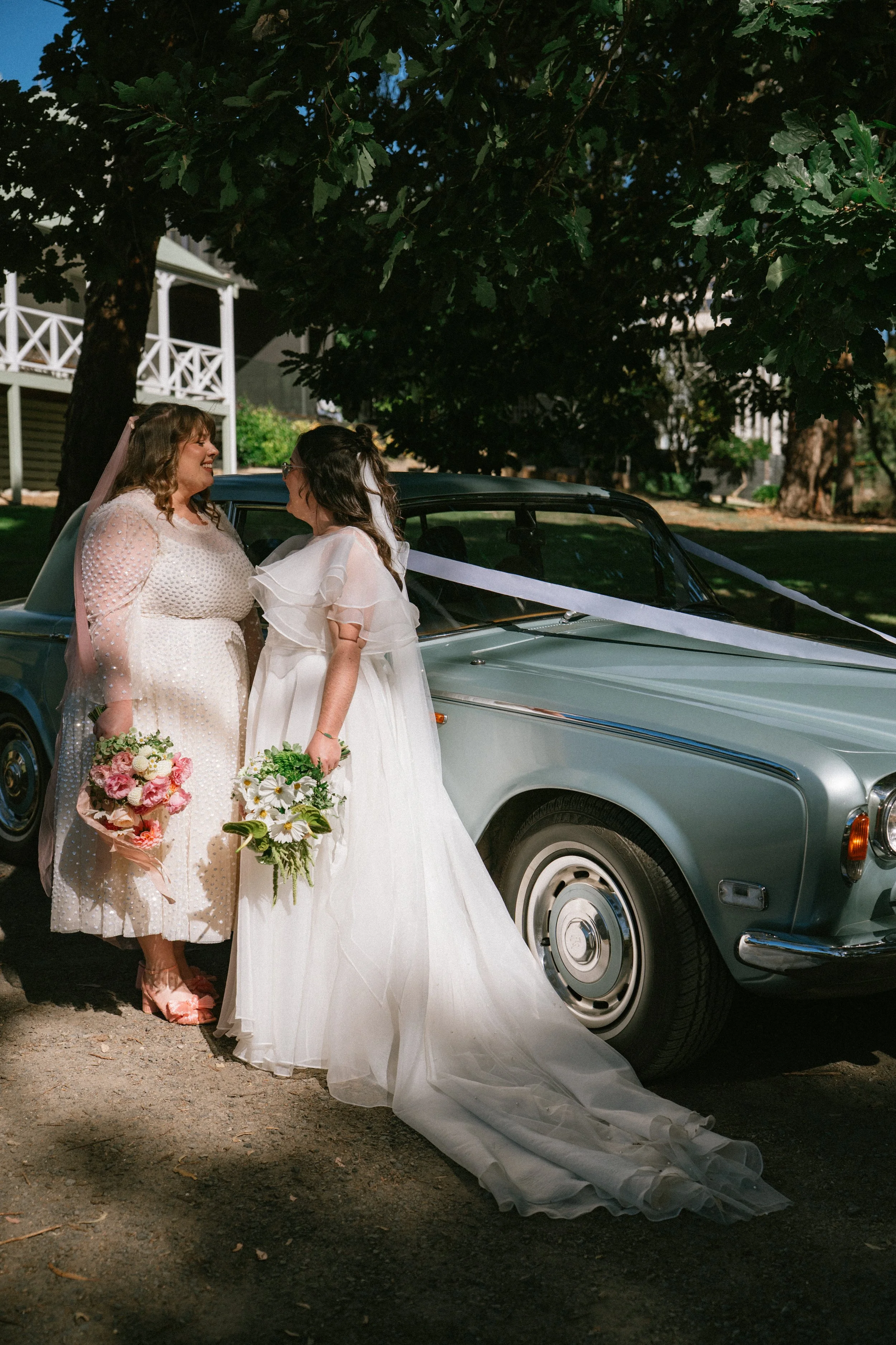 Two brides standing alongside vintage Rolls Royce for their Ballarat-Daylesford wedding