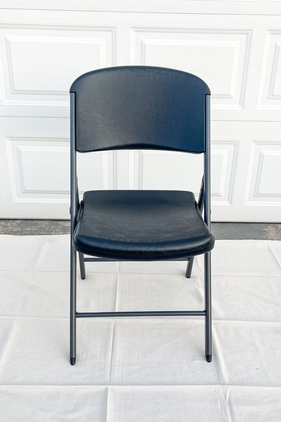 Black folding chair with metal frame on white background