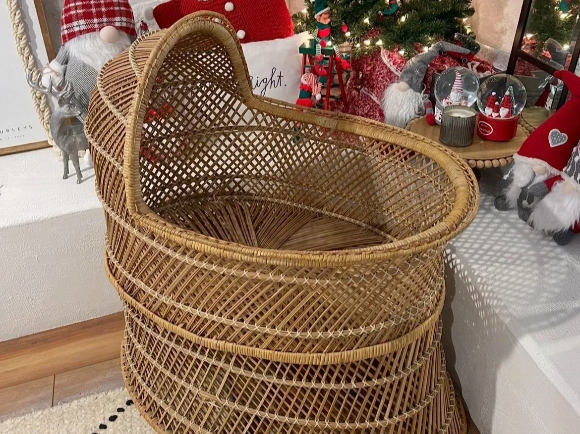 Wicker chair with holiday decorations including gnomes, a reindeer figurine, candles, and a Christmas tree.