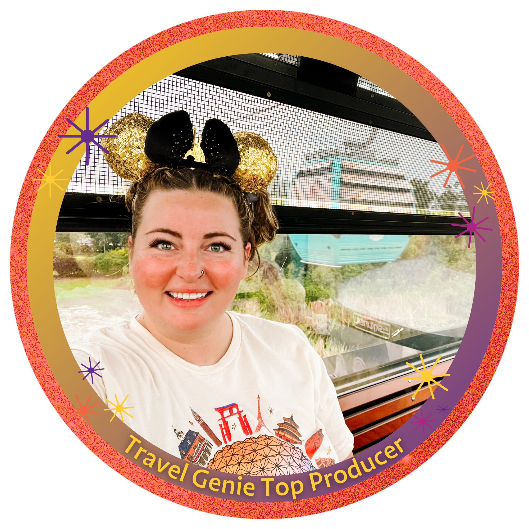 A young woman taking a selfie inside a colorful amusement park ride with forested scenery in the background. She is wearing a white T-shirt with landmarks and has a Minnie Mouse ears headband with gold sequined ears and black bow.