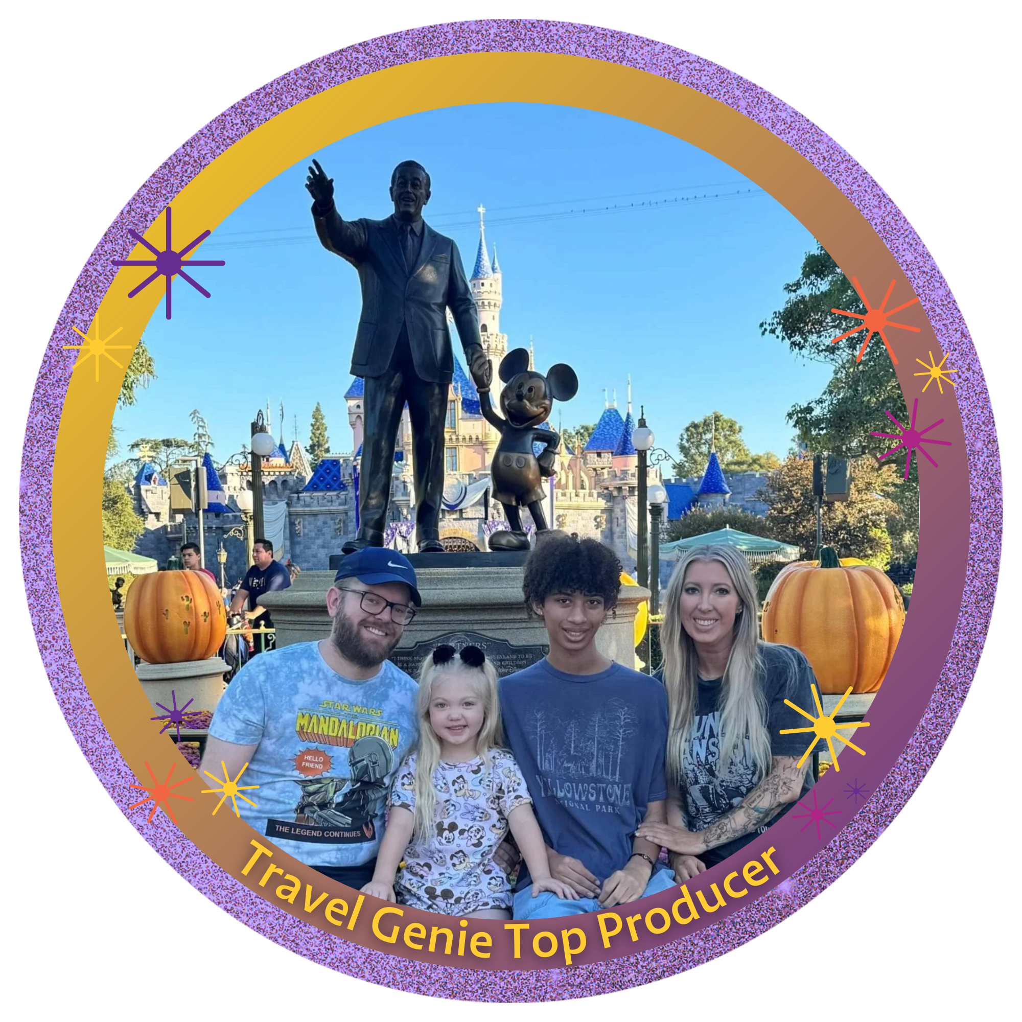 A family of four sitting in front of a Disney castle with a statue of Walt Disney and Mickey Mouse, on a fall day with pumpkins and trees.