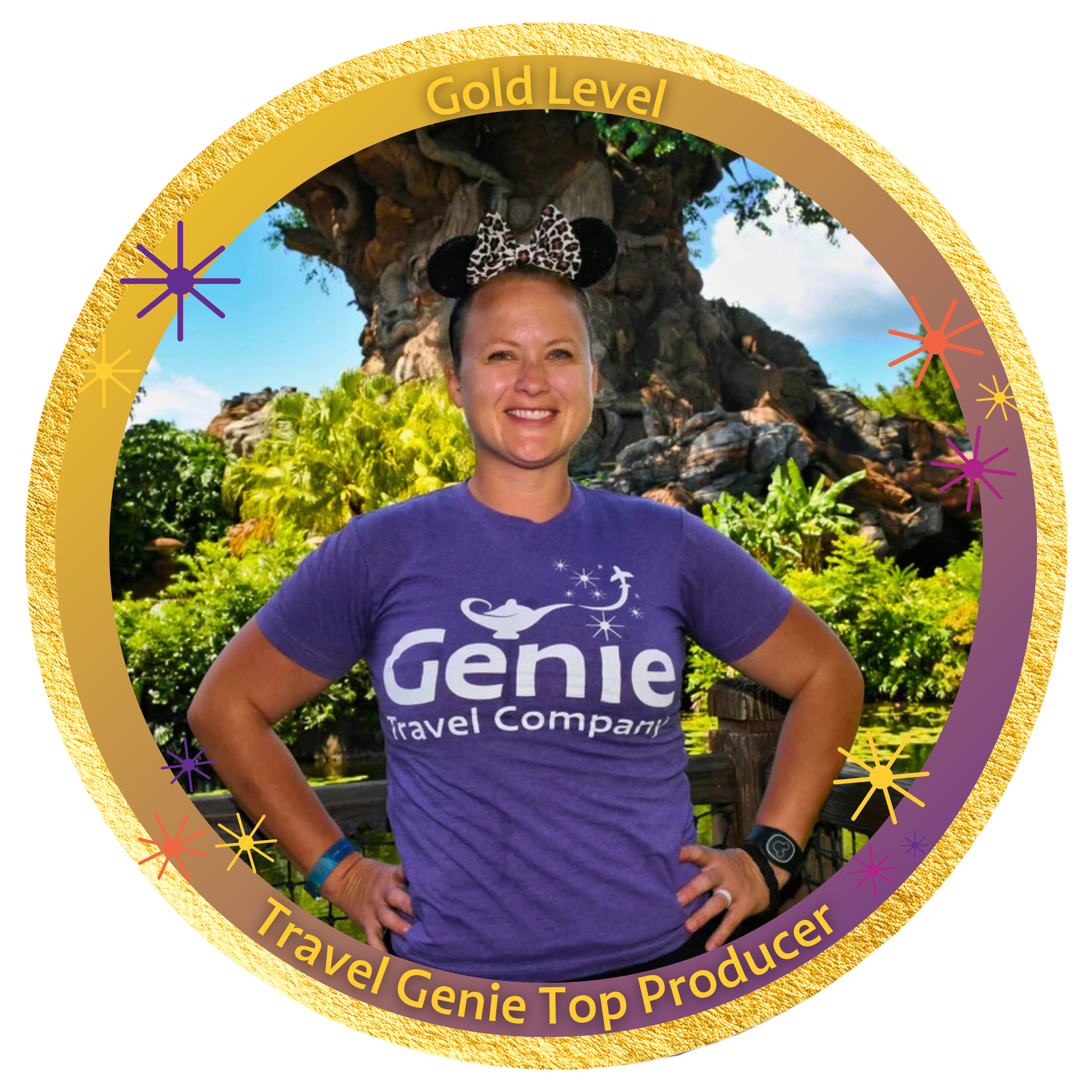 A woman standing outdoors in front of a large, themed tree, wearing a purple 'Genie Travel Company' t-shirt and Minnie Mouse ears headband with a leopard print bow.