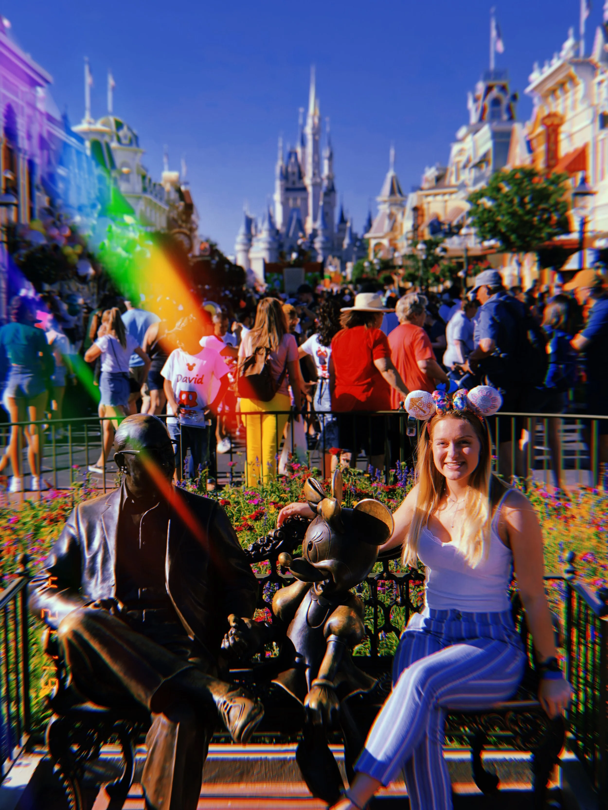 A woman sitting on a park bench with Mickey Mouse and Walt Disney statues in front, in front of Cinderella Castle at Magic Kingdom, Disney World.