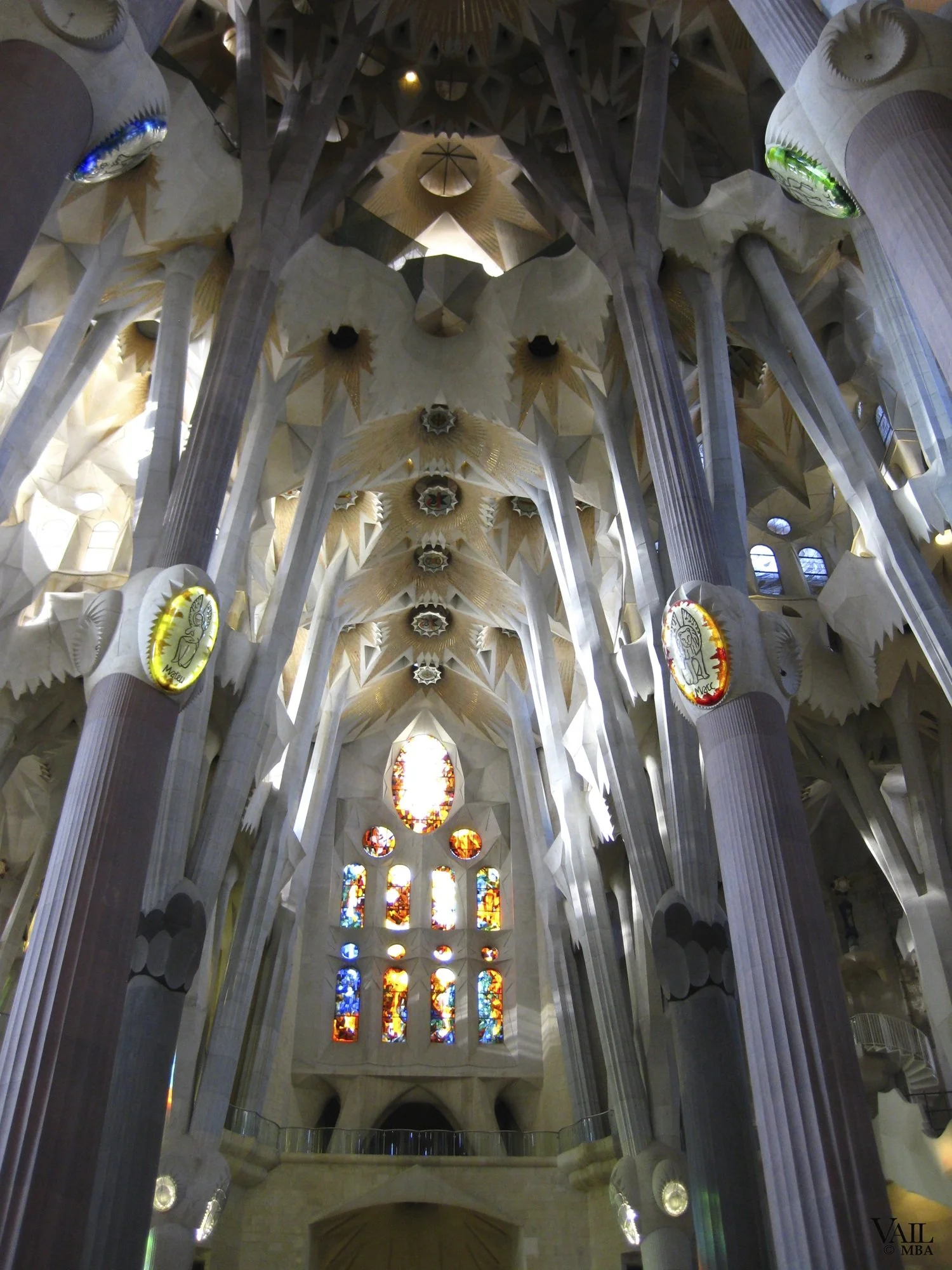 Interior view of the Sagrada Familia in Barcelona with high ornate ceilings, tall stone columns, and stained glass windows.