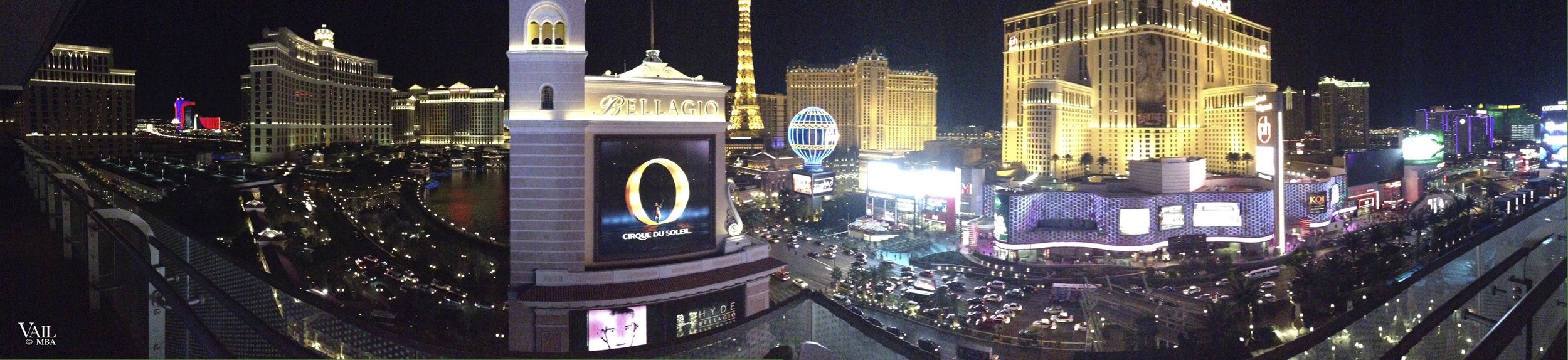 Nighttime view panoramic view of the Las Vegas Strip with illuminated buildings, billboards, and the Eiffel Tower replica at Paris Las Vegas.