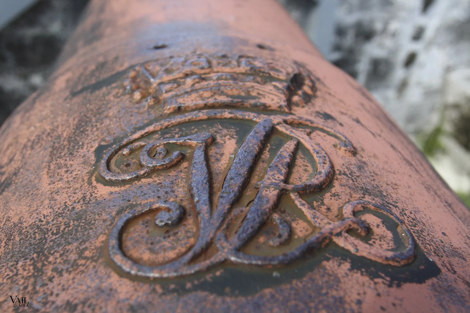 Close-up of a weathered cannon with embossed insignia.