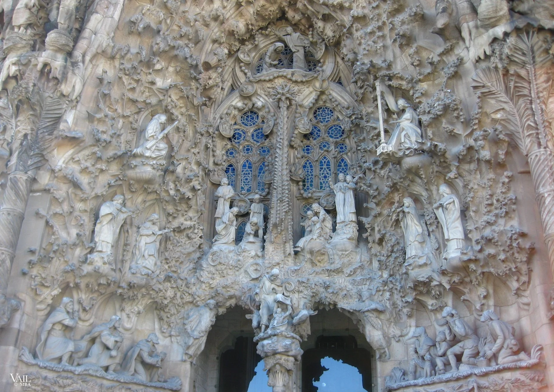 Close-up of the detailed stone facade of the exterior of the Sagrada Familia in Barcelona, with intricate sculptures depicting religious scenes and figures surrounded by elaborate organic motifs.