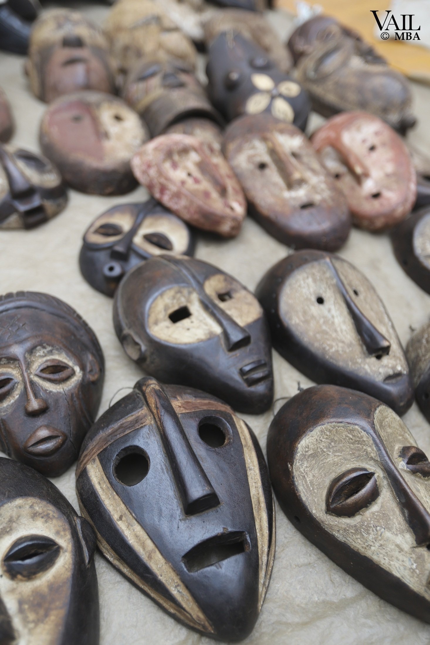 Close-up view of traditional wooden masks with carved faces at a market in Kenya.