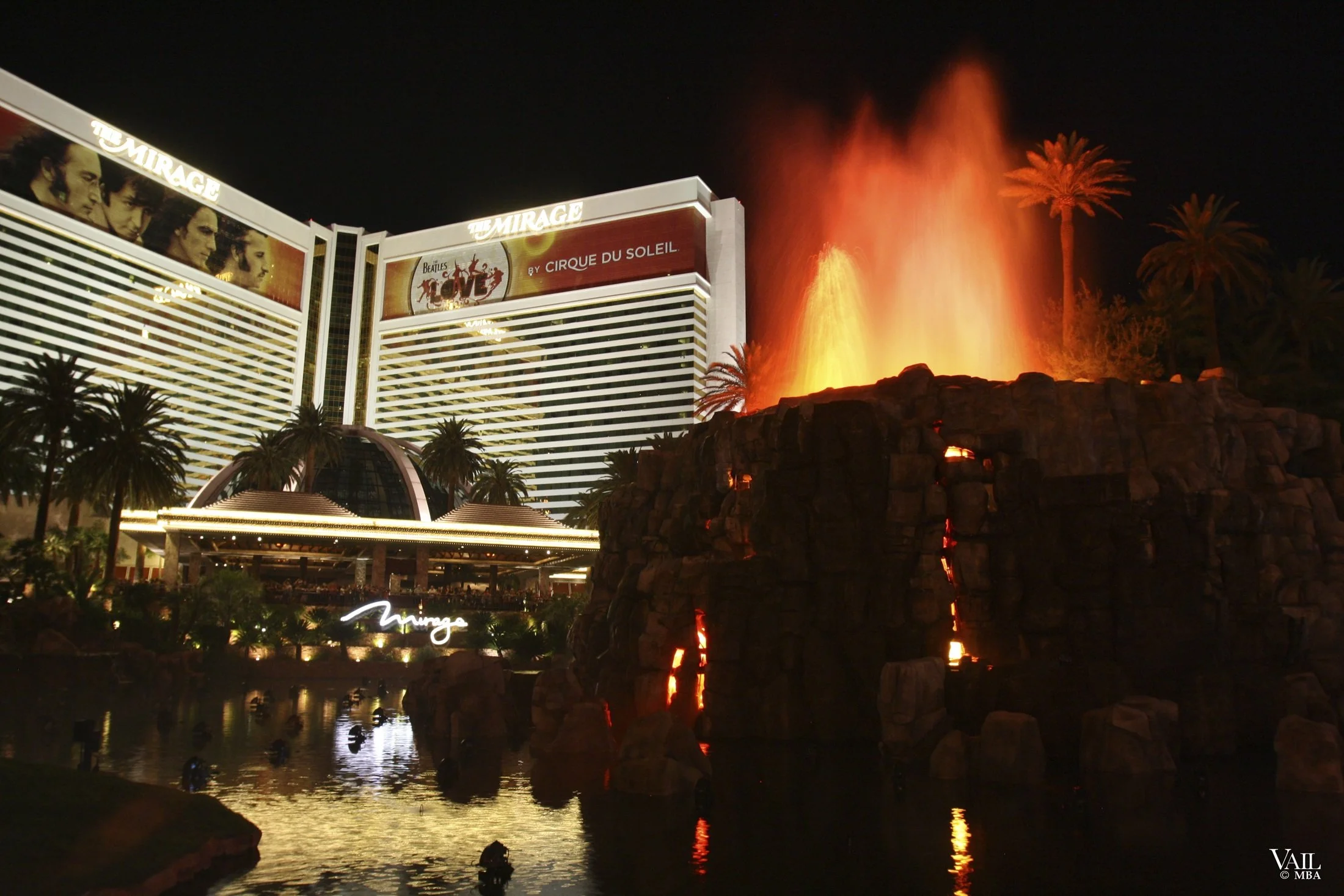 Night photo of the Mirage hotel and casino in Las Vegas with volcano erupting.