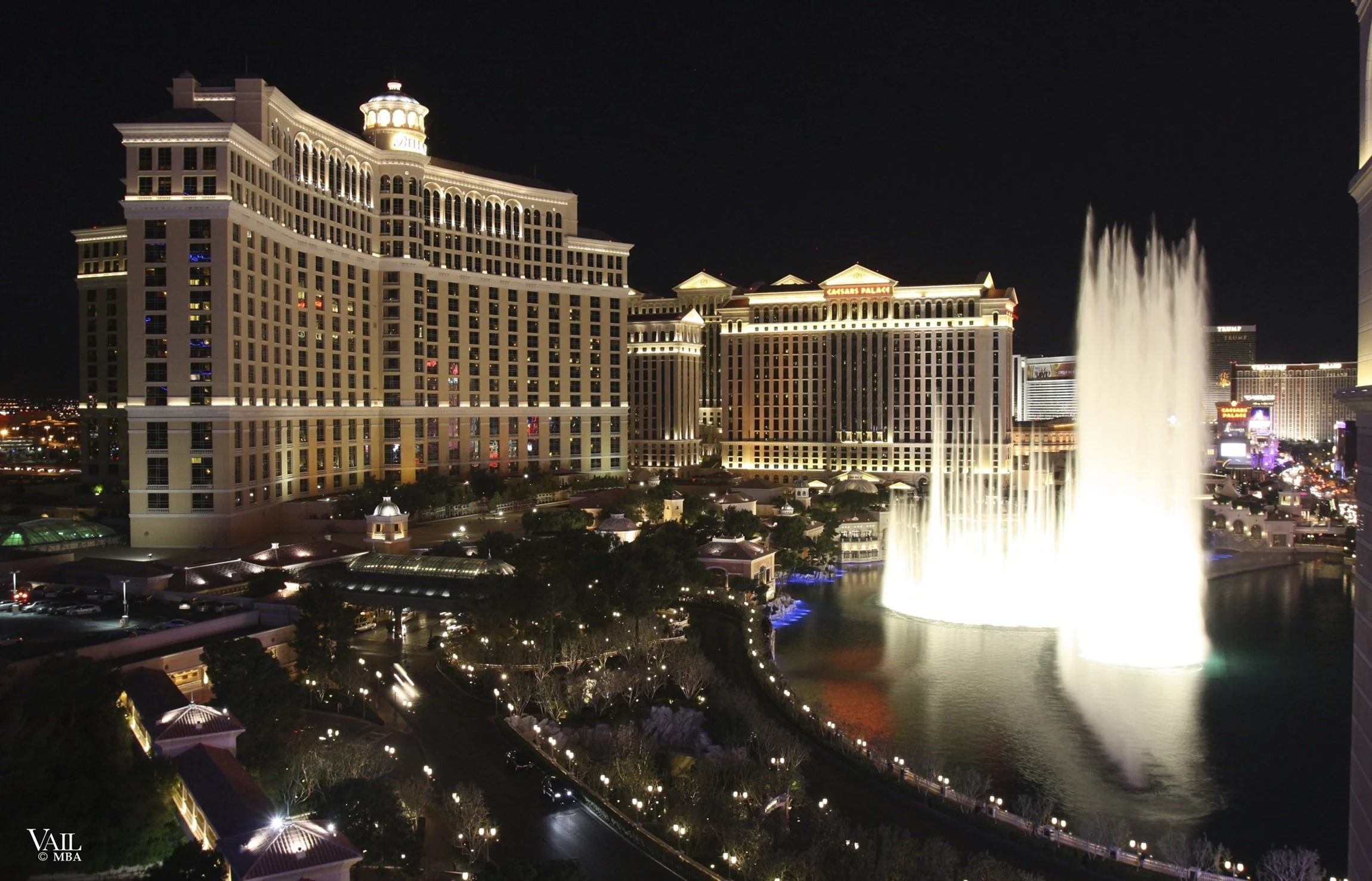 Night photo of the Bellagio Fountains with the Las Vegas Strip in the background.