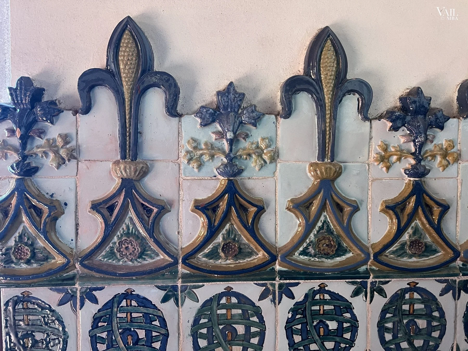 Close-up of decorative ceramic tiles featuring floral and fleur-de-lis patterns in blue, gold, and cream colors, Portugal.