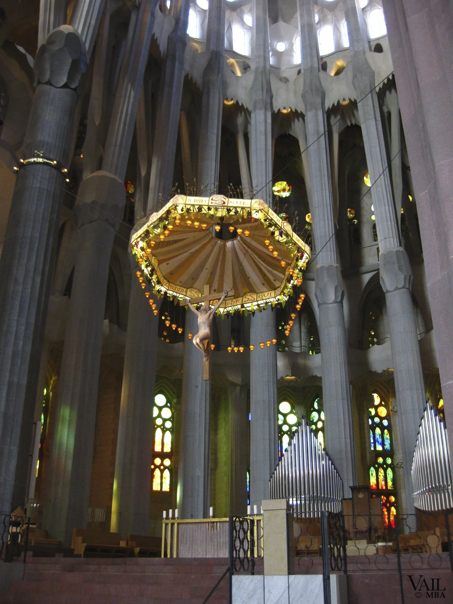 Interior of the Sagrada Familia altar with tall stone columns, stained glass windows, and pipe organ pipes in the background, Barcelona, Spain. 
