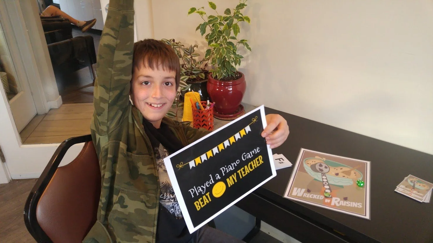 Smiling boy holds sign Played Piano Game Beat my Teacher!