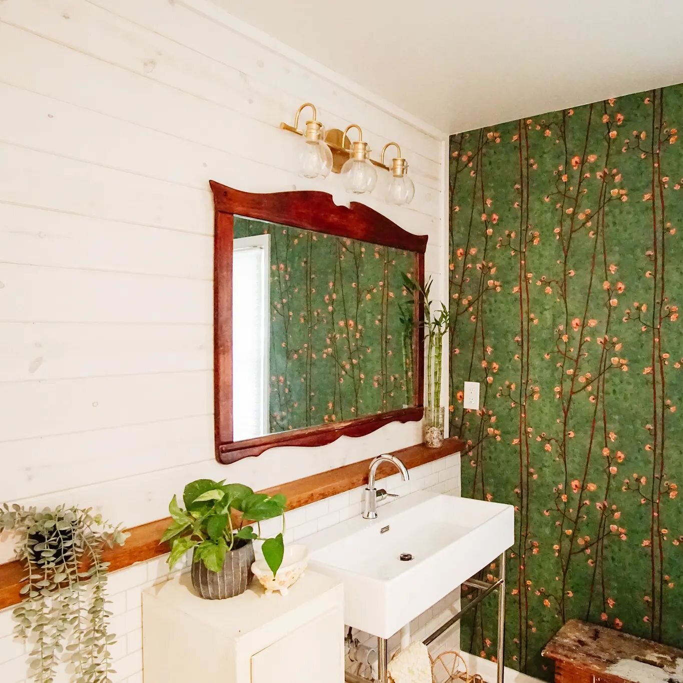 This ensuite bathroom is the right balance of eclectic and charming. White washed ship lap is paired with clean subway tile and gorgeous richly colored wallpaper. We love the vintage mirror, plants, and furniture against this backdrop. 

The owner is