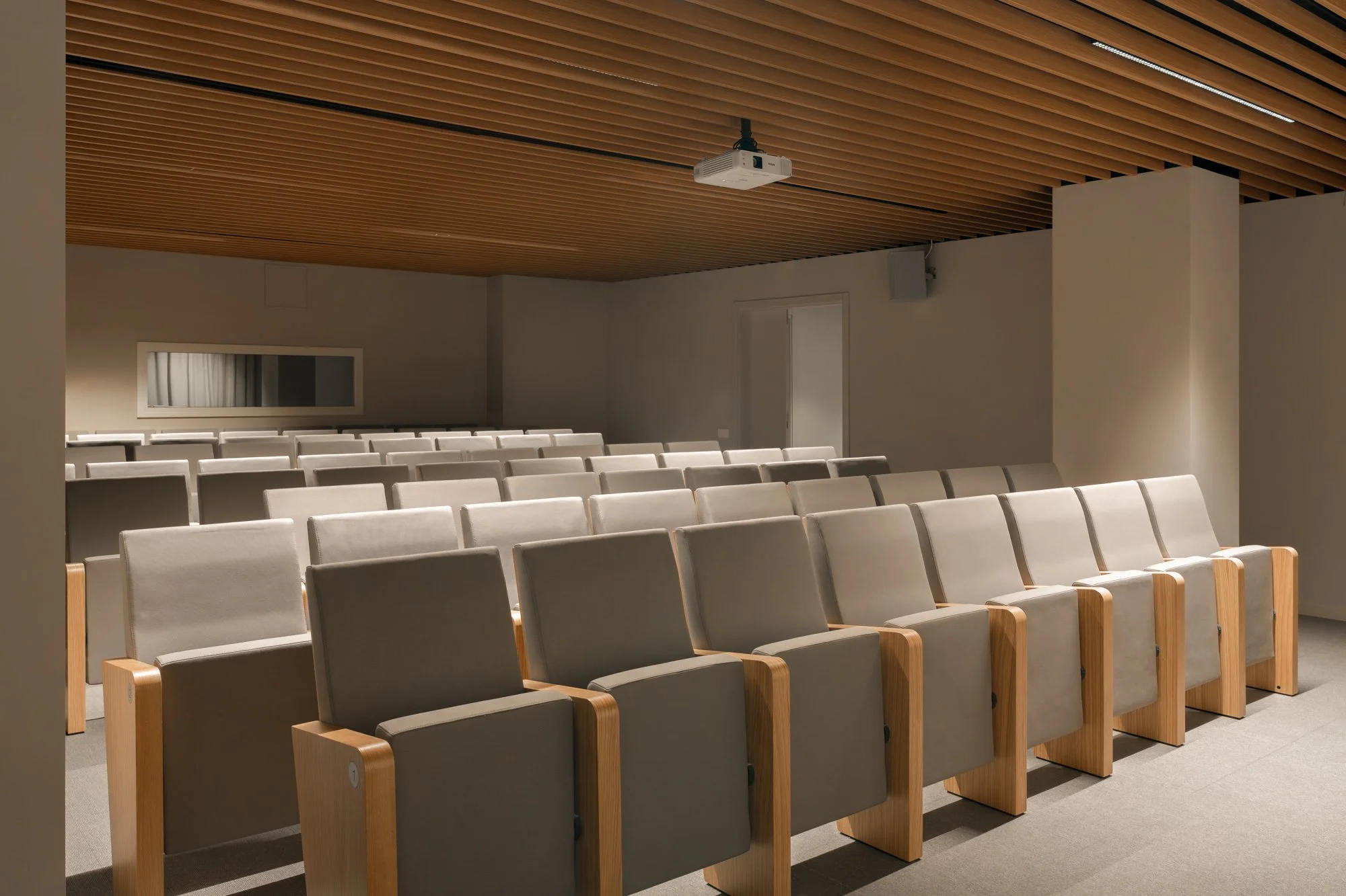 Sala de conferencias vacía con sillas cómodas y una proyección en el techo.