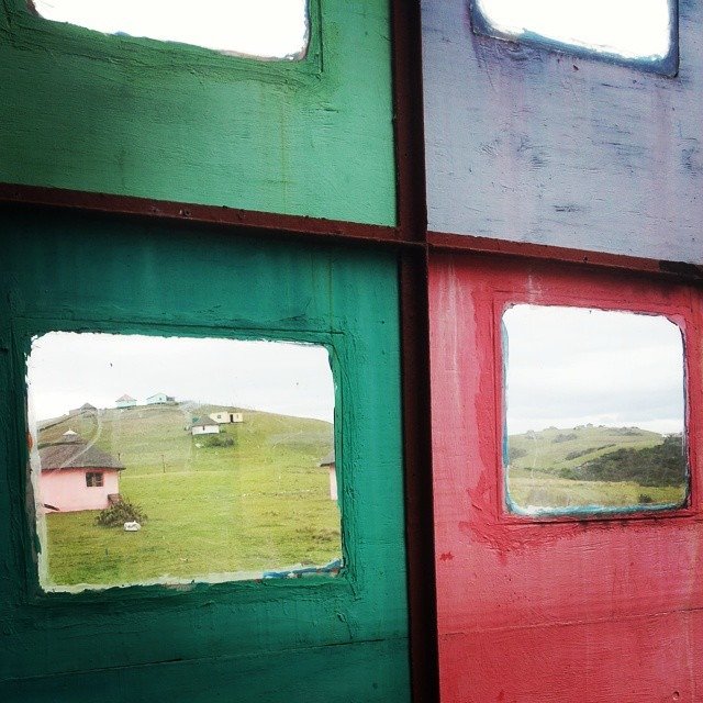 Blick aus einem Fenster auf die Landschaft und einige Rondavels