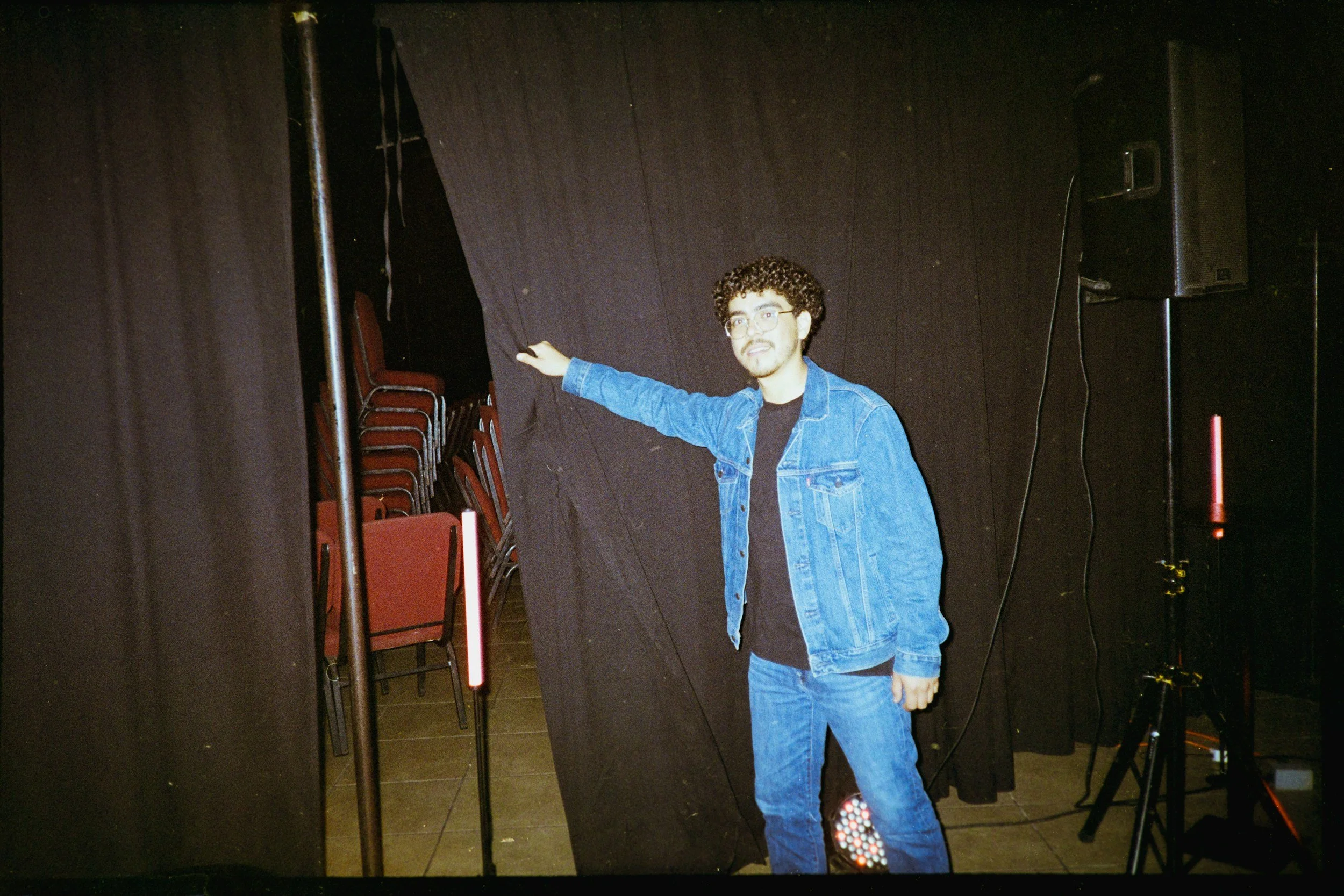 man pulling the curtain behind the scenes of a public speaking stage