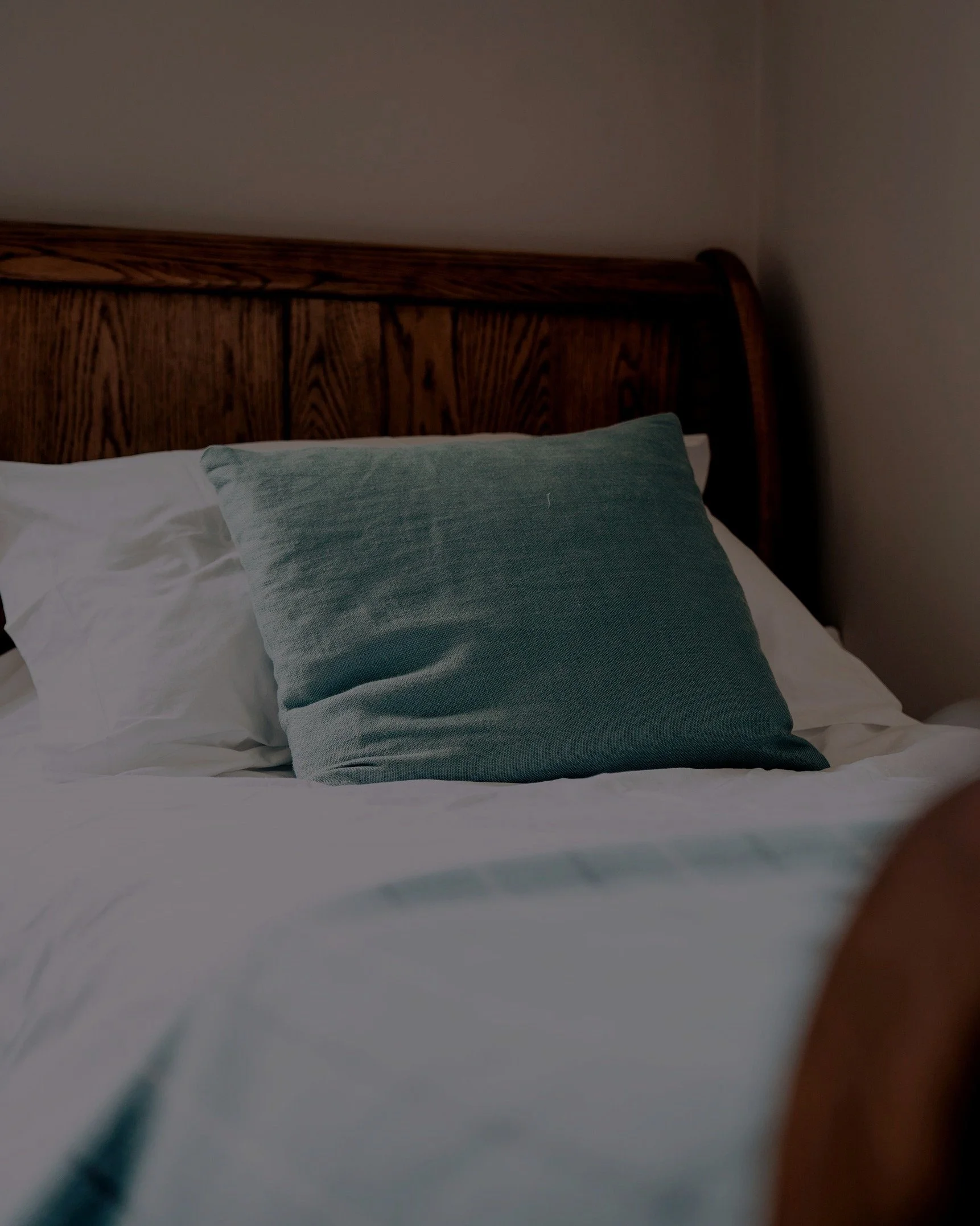 Made bed with a decorative blue pillow in the Buck Suite, Moreton House, North Devon.