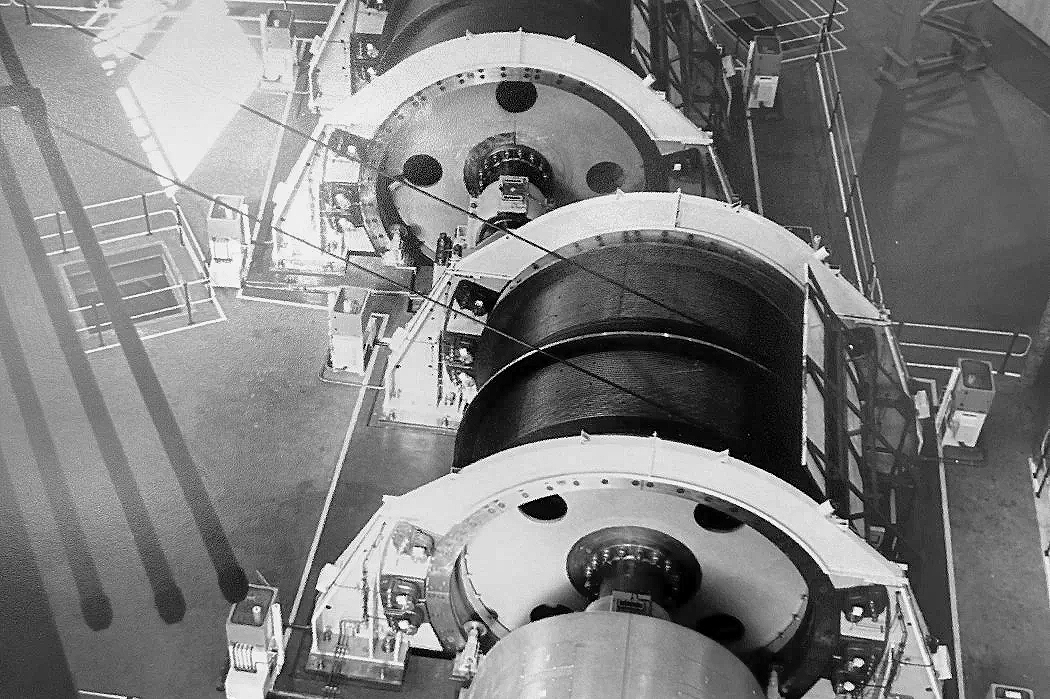 Close-up of three large industrial cylindrical components or turbines arranged vertically on a platform.