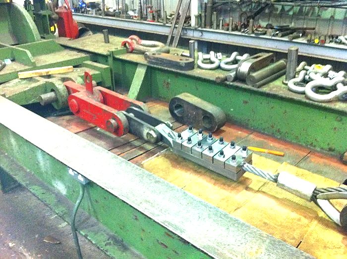 Industrial workshop with green machinery and tools, including metal components and chains, on a workbench.