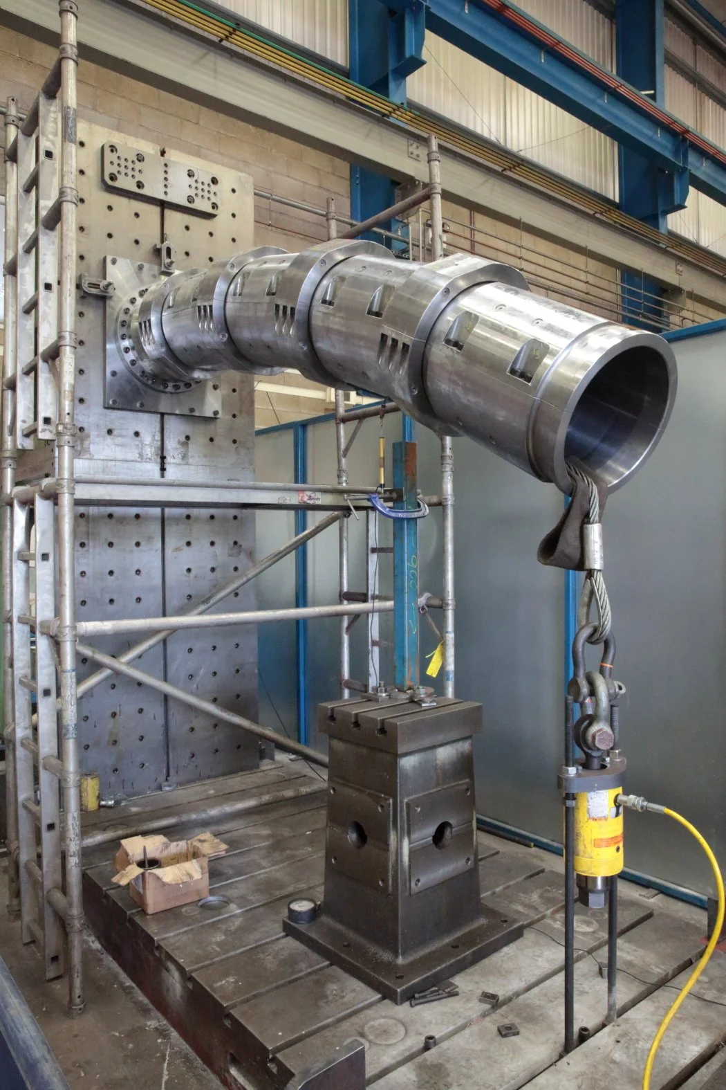 Large industrial pipe, possibly for heavy machinery or construction, mounted on a metal frame within a factory or manufacturing setting.