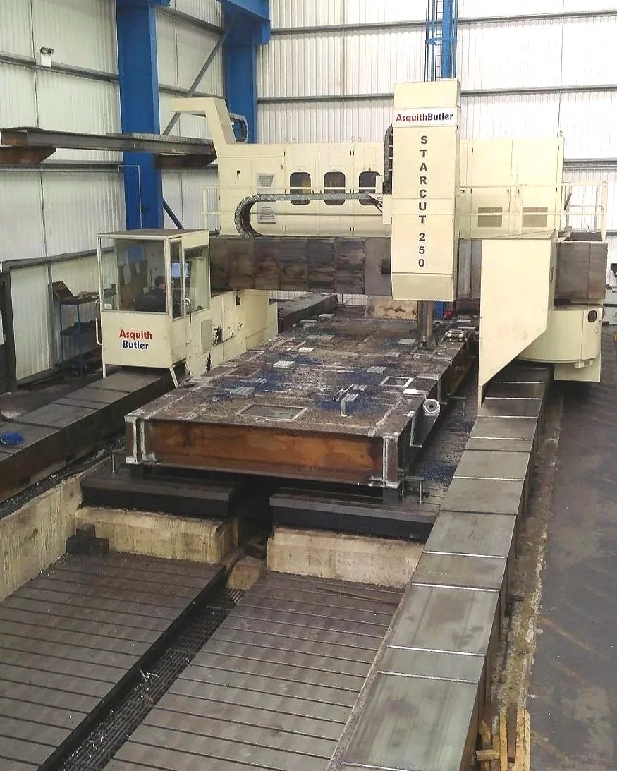 Large industrial CNC machine cutting metal at a manufacturing facility.