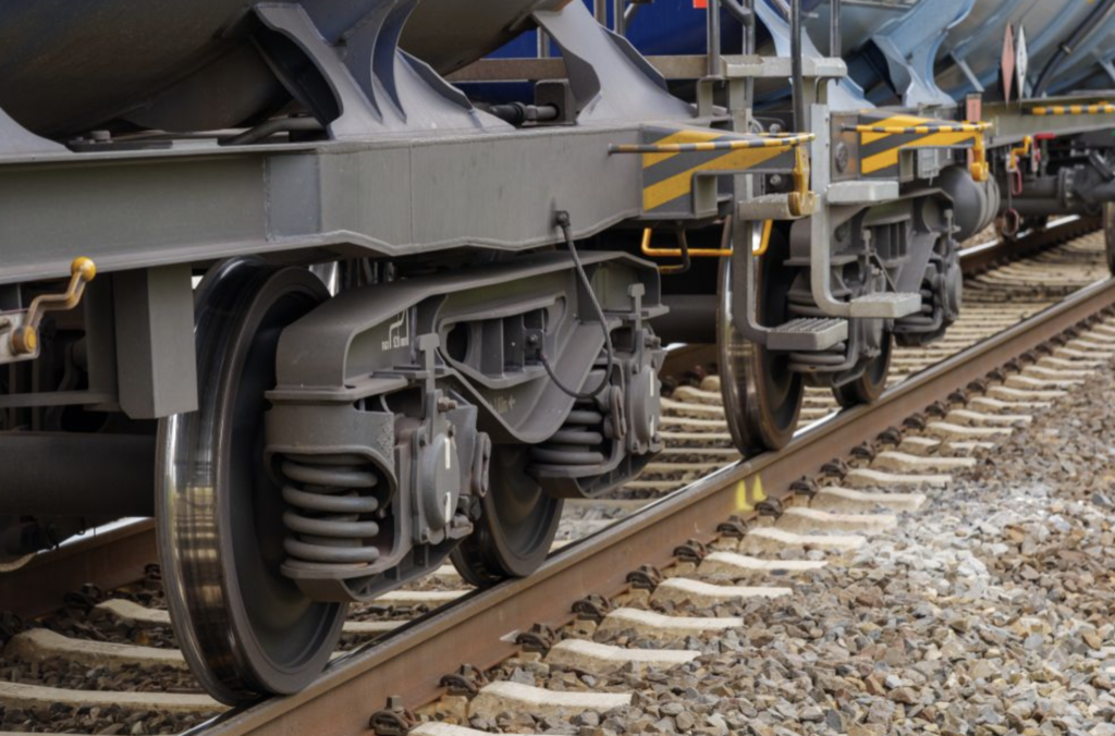 Close-up of train wheels and suspension on railway tracks.