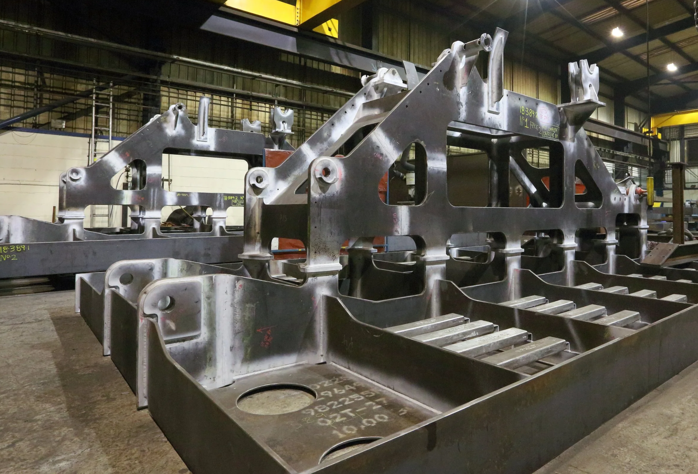 Steel aircraft fuselage components stacked in a factory warehouse.