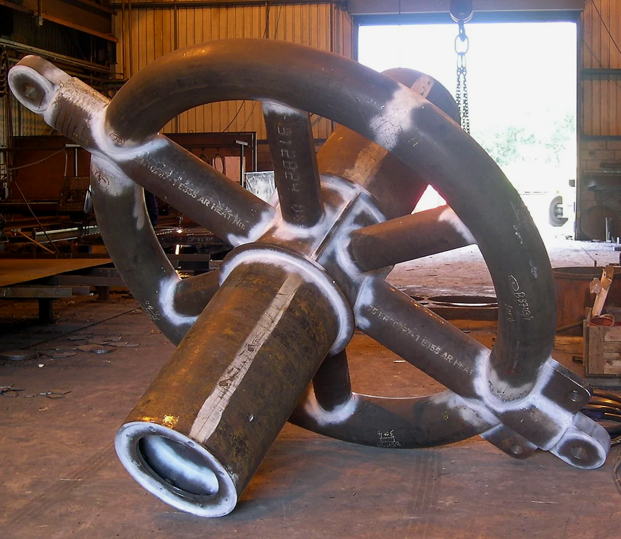 Large subsea mooring steelwork inside a workshop.