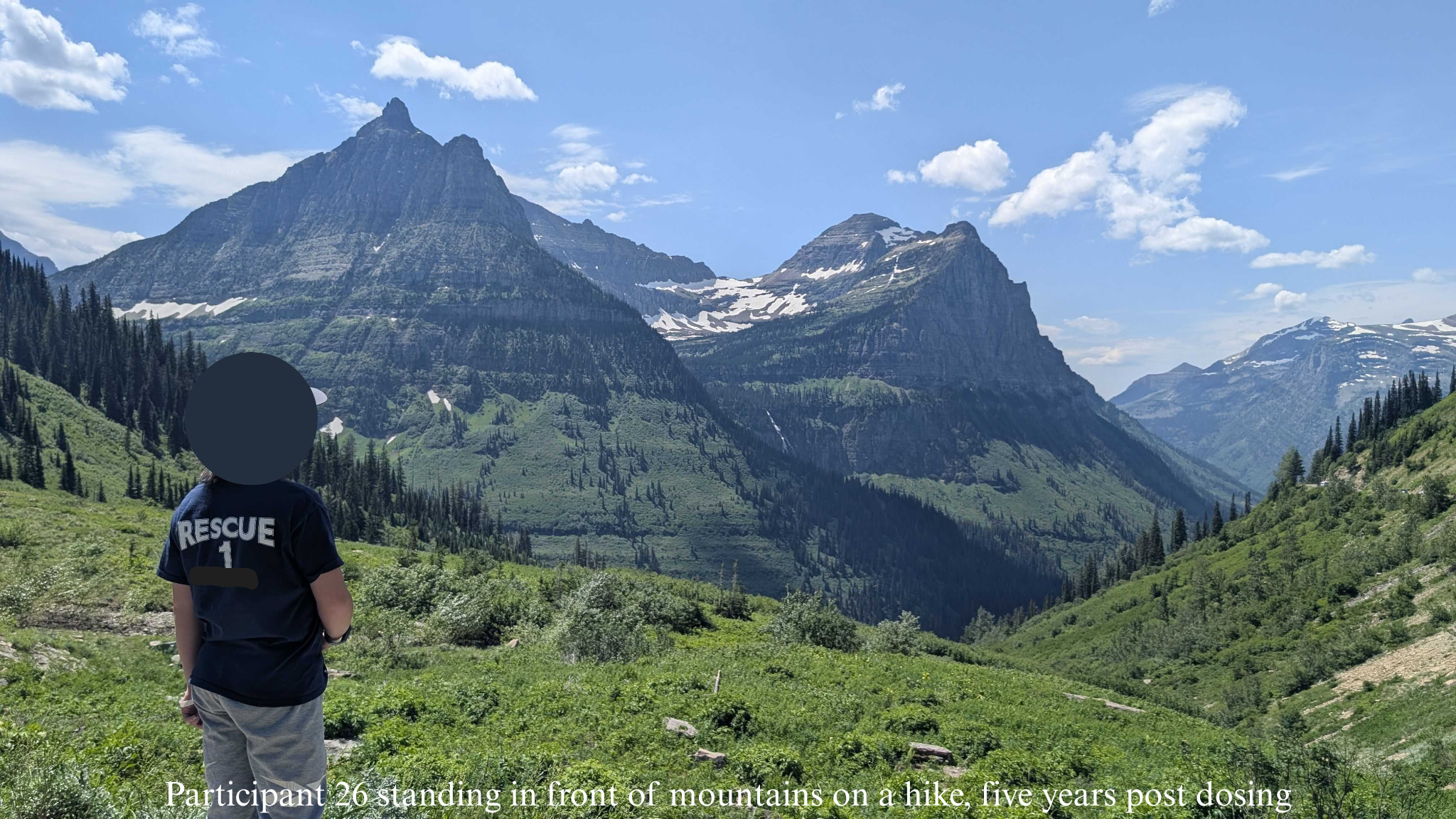 Participant 26 standing in front of mountains on a hike 5 years post-dosing