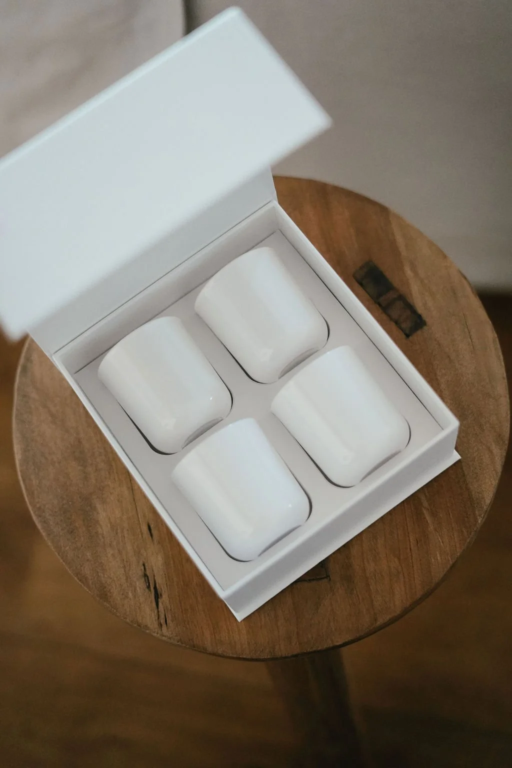 Woman sitting on a green sofa holding a Starbucks coffee cup, with legs crossed. A record player and vinyl records are in the background on the left, and a lit candle is on a wooden trunk in the foreground.
