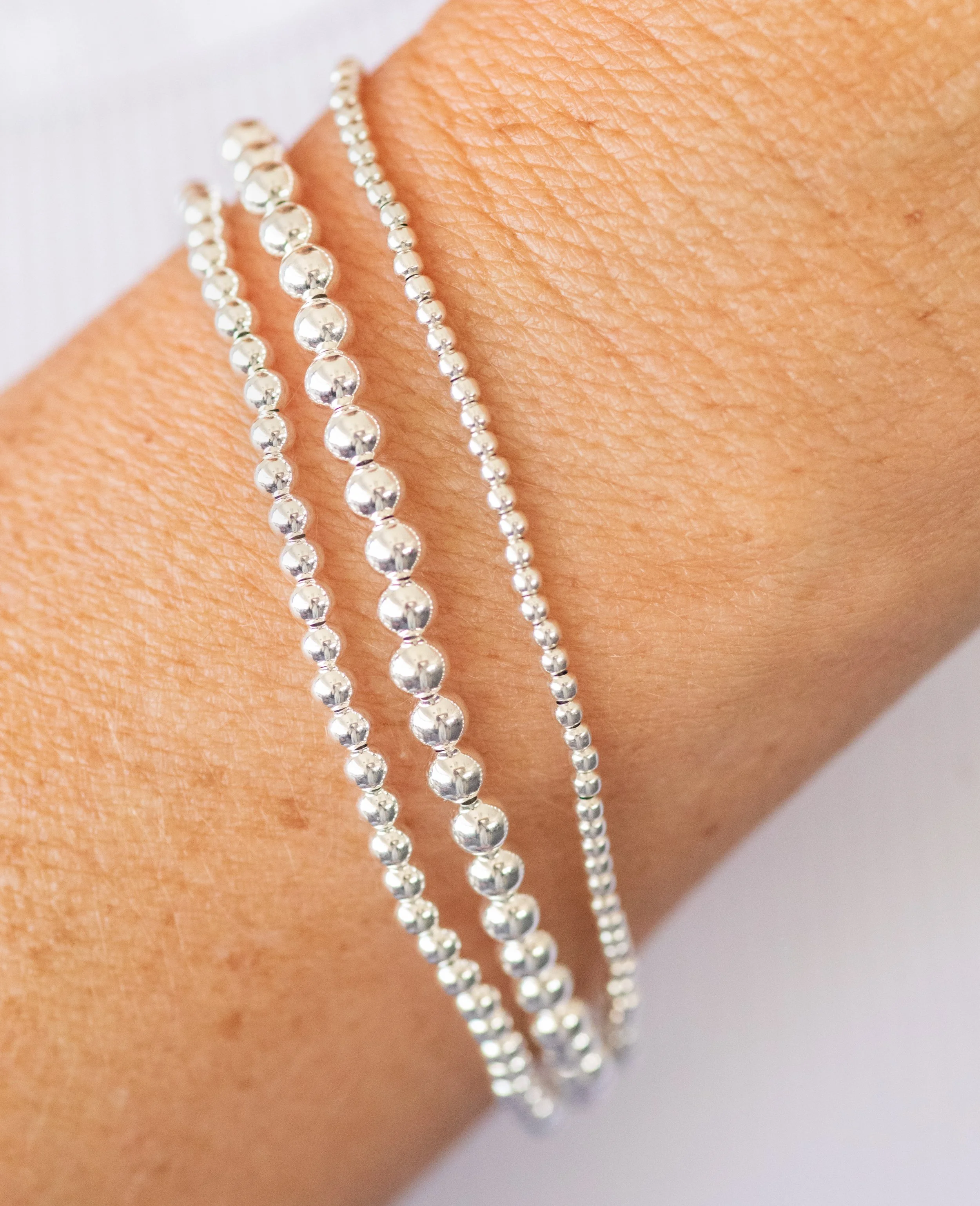 Three silver bead bracelets on a person's wrist, close-up shot.