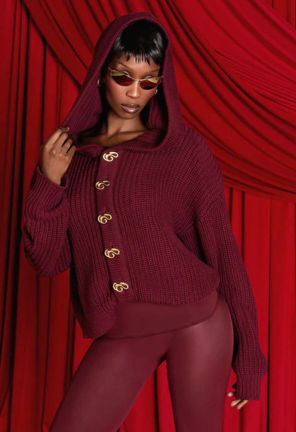 Model wearing Kai Collective Nori hooded cardigan in burgundy with matching tights and sunglasses
