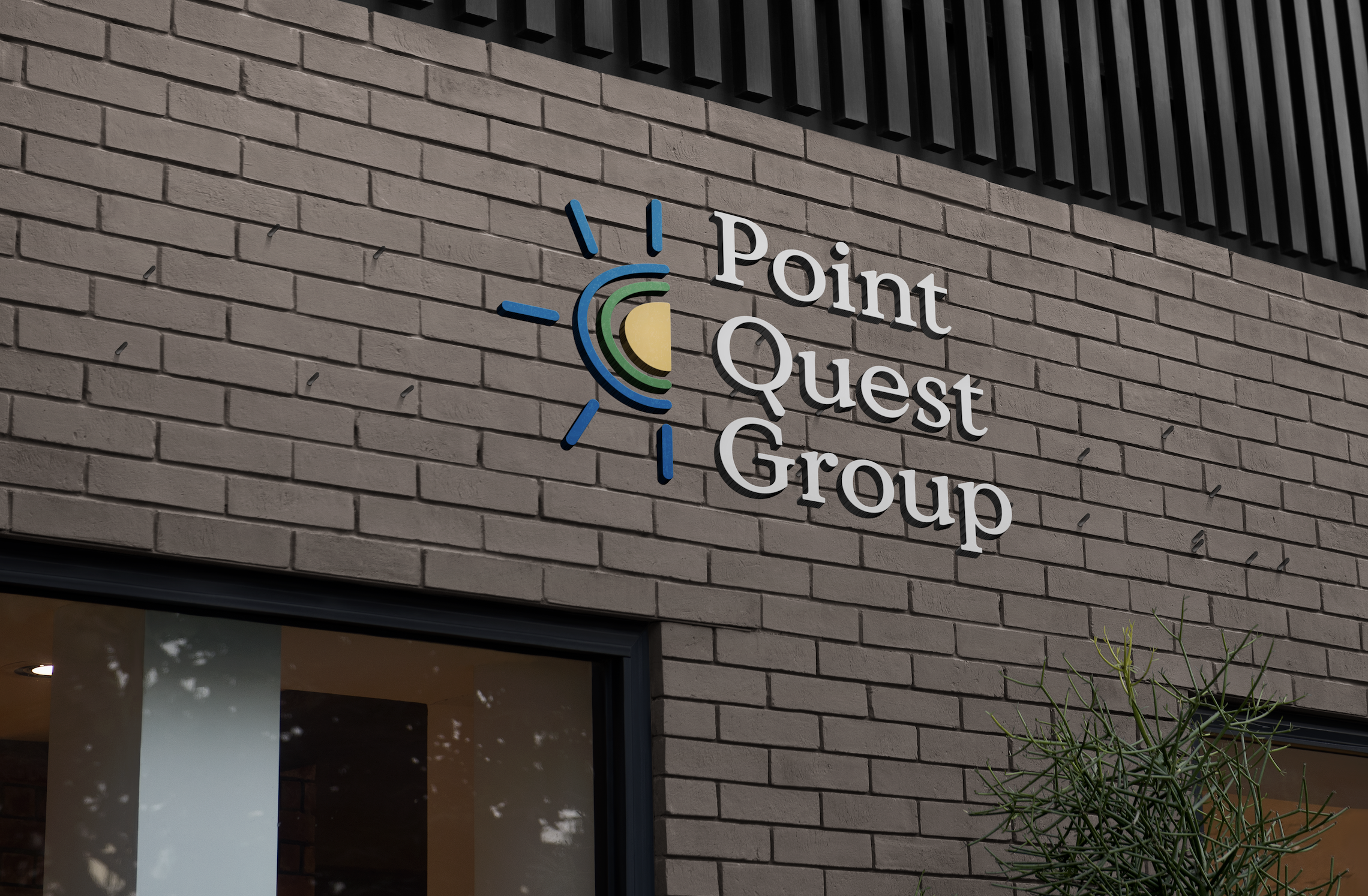 Sign on a brick building reads 'Point Quest Group' with a colorful logo of a stylized sun or star and green, blue, and yellow circles.