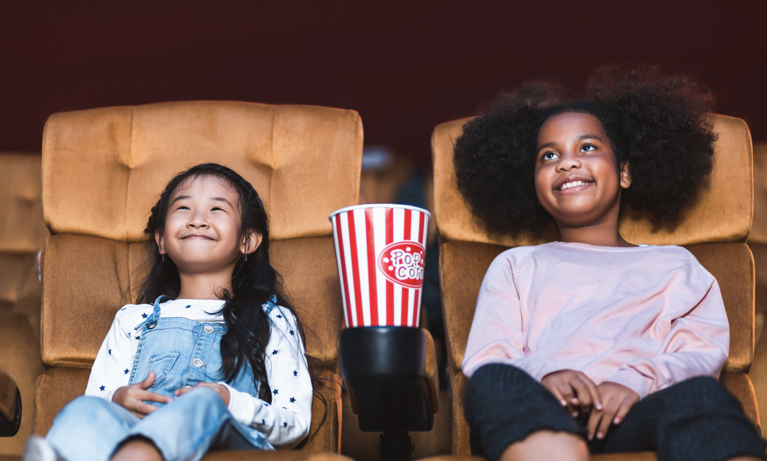 Two tween girls watching a movie film and eating popcorn