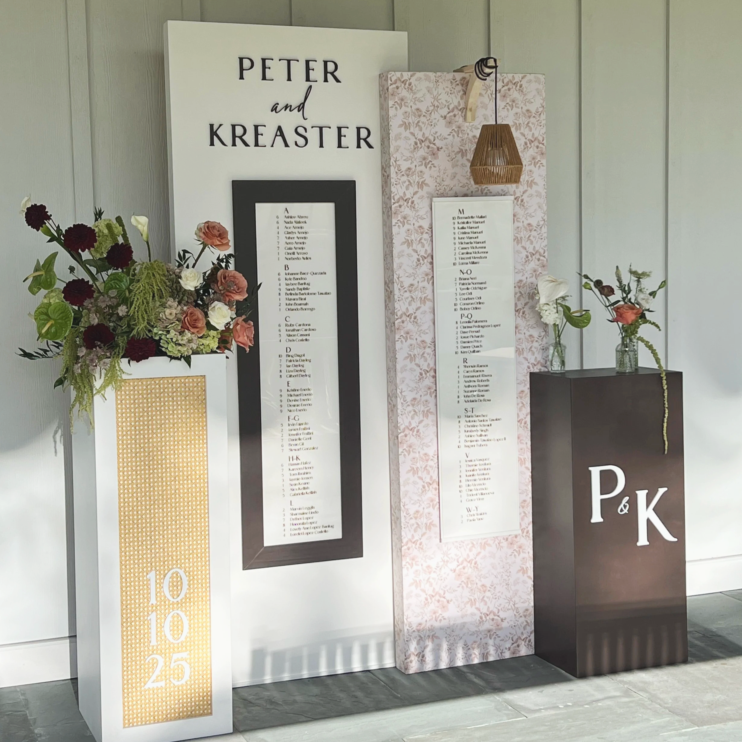 Wedding seating chart display with floral arrangements, a freestanding luxury setup featuring pendant lighting and custom design at Chester County, PA, wedding reception.