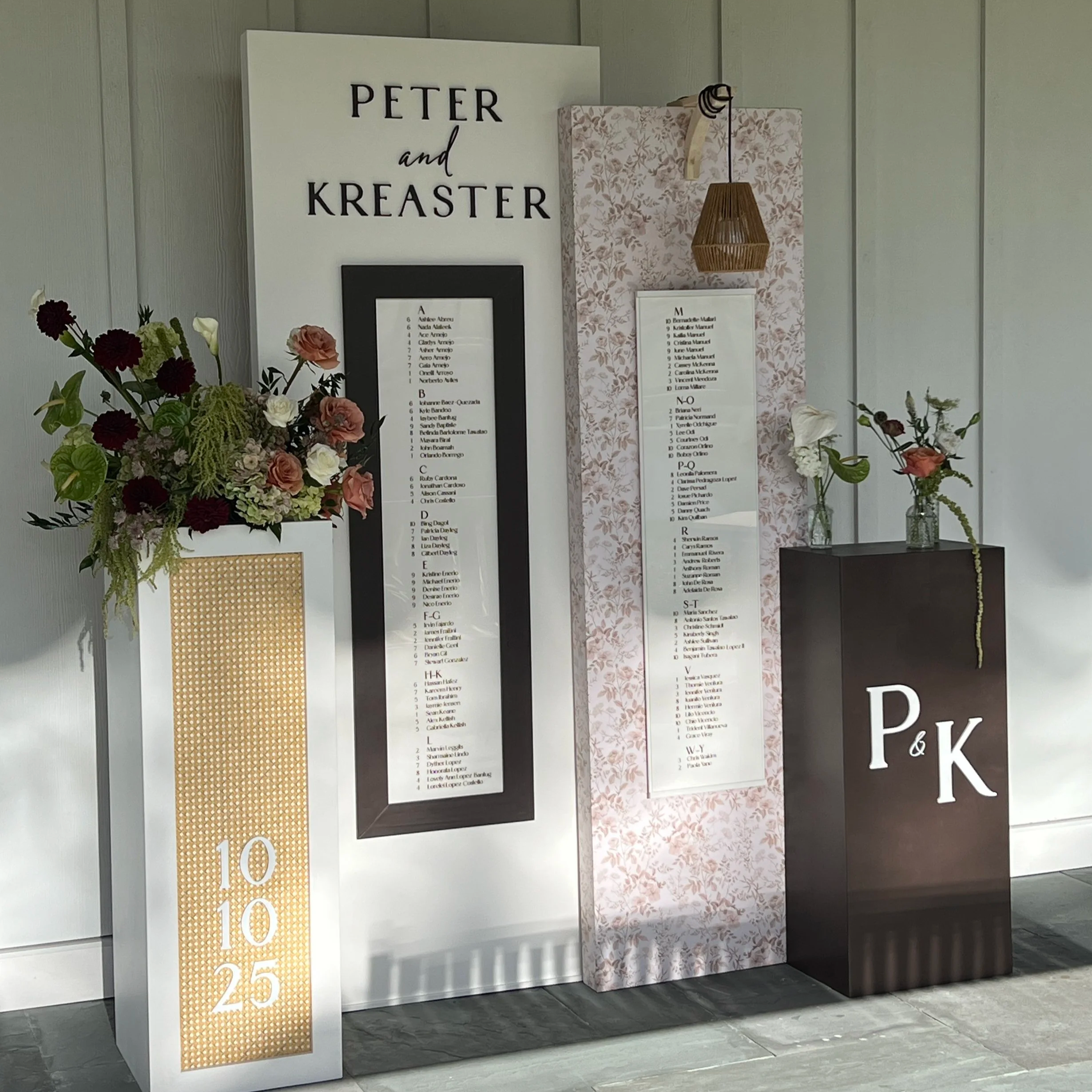 Wedding seating chart with two pedestals, two vertical display panels featuring custom lettering, rattan accents, and woven pendant light setup at a luxury wedding in Chester County, PA