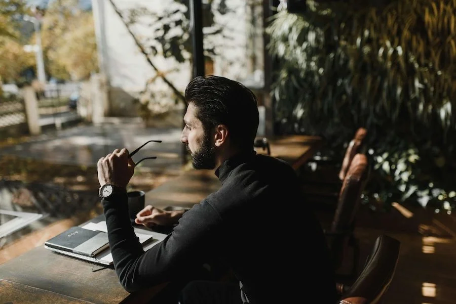 man with glasses thinking about brand's true purpose at desk