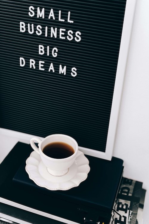 photo of coffee cup with sign behind it that says small business big dreams