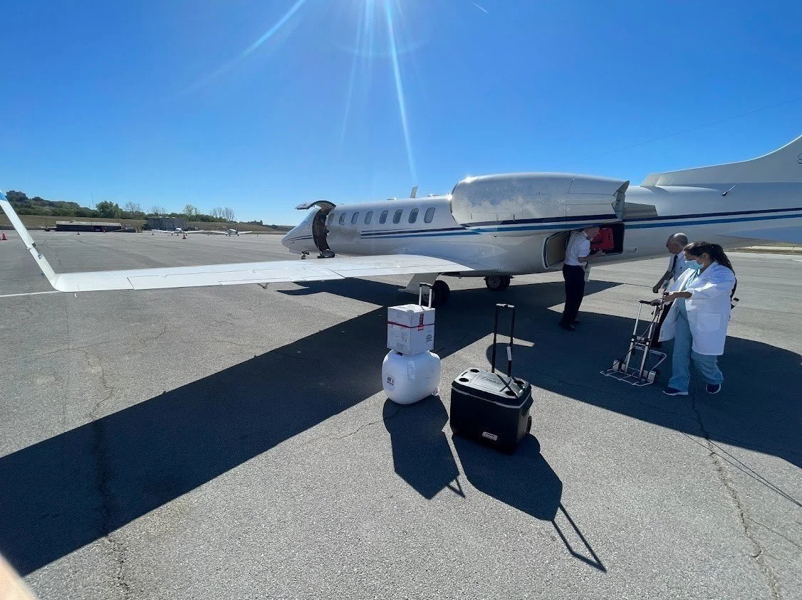 People boarding a private jet at an airport on a sunny day.