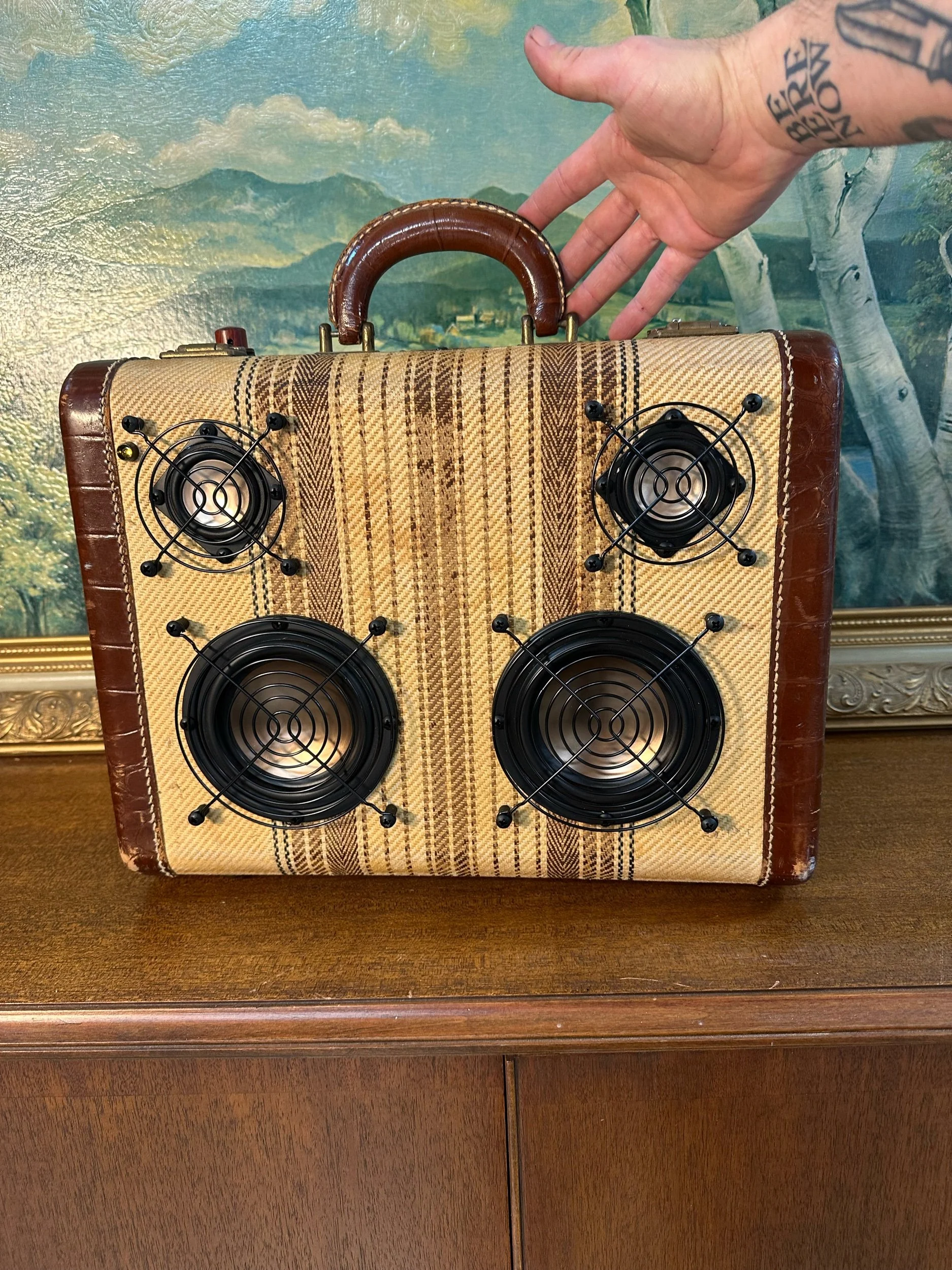 Vintage suitcase with built-in speakers on a wooden surface