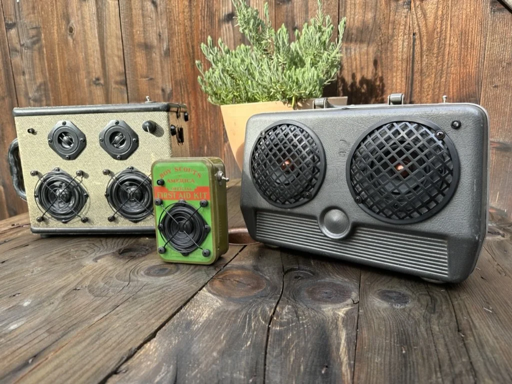 Vintage speakers and a Boy Scouts of America first aid kit on a wooden surface.